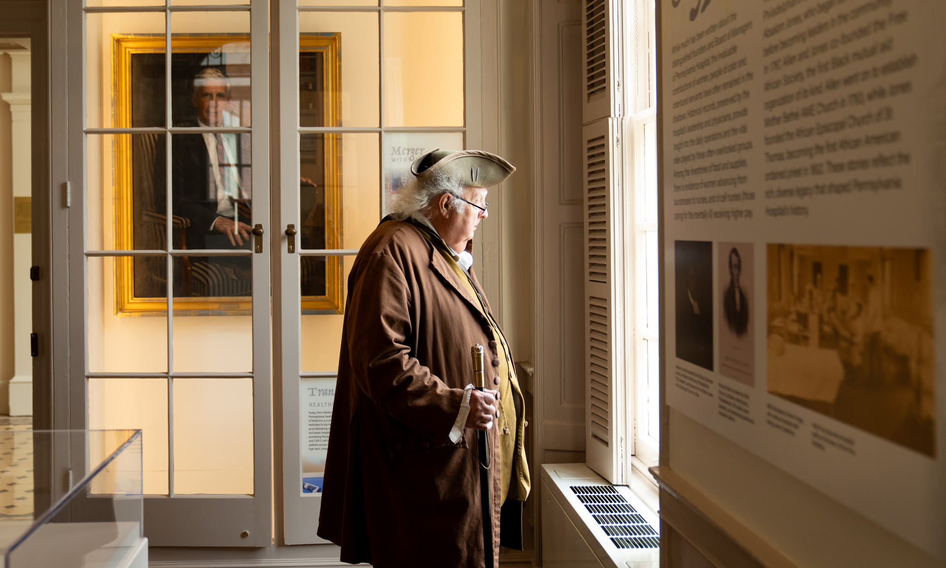 A reenactor of Benjamin Franklin looking out of a Pine Building window