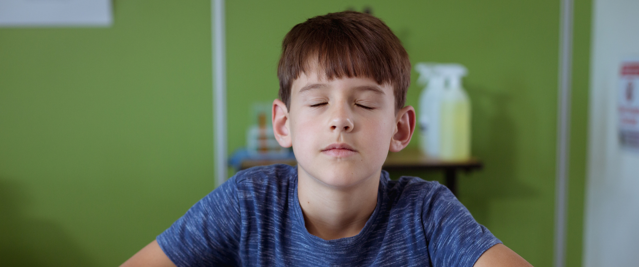 Blind caucasian  boy sitting with eyes closed reading braille book with fingers. 