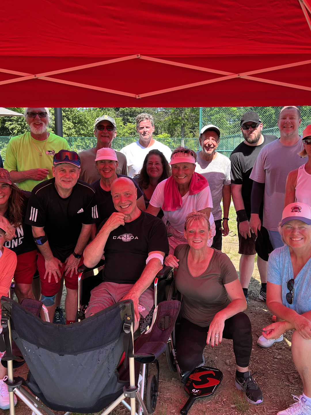 A group of adults dressed for outdoor recreation in a group photo with pickleball paddles