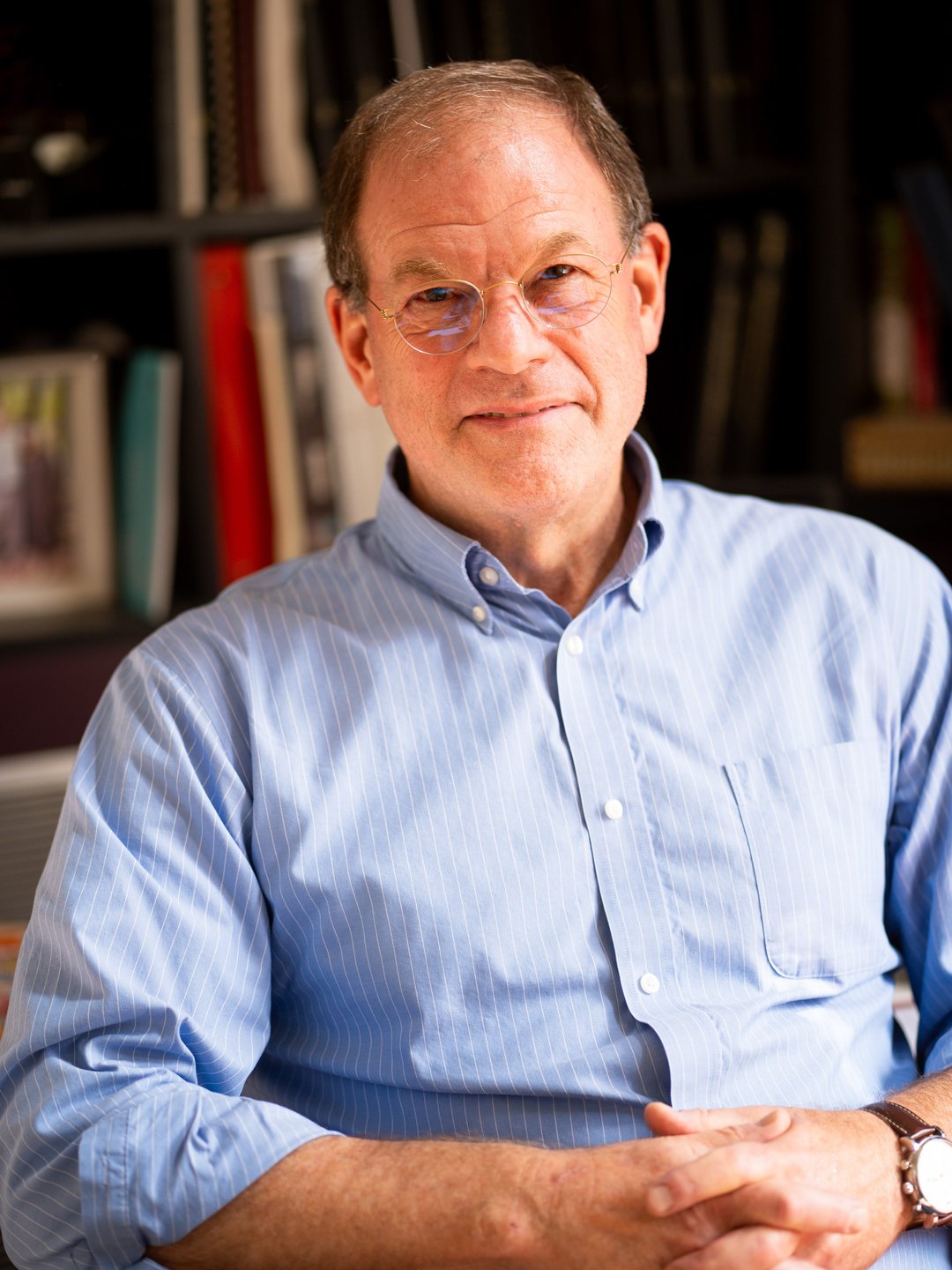 A portrait of Brian Litt sitting in front of books