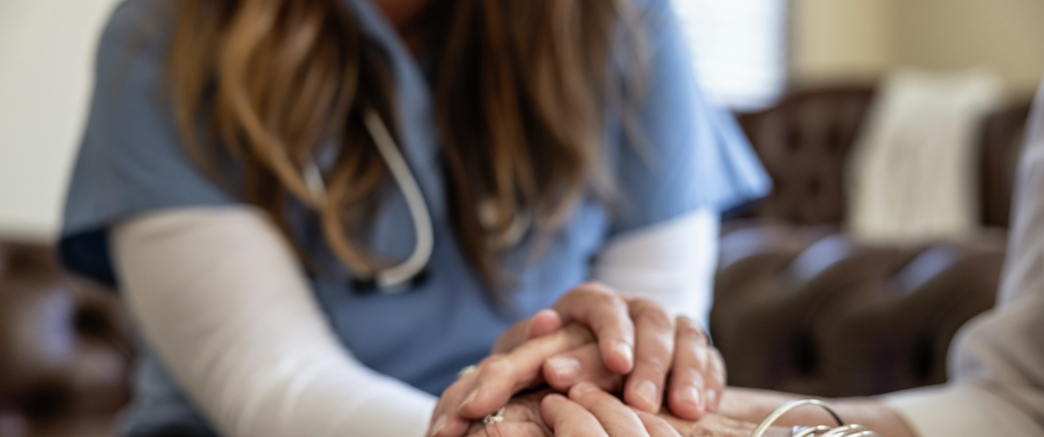 A healthcare worker holds the hand of an elderly patient