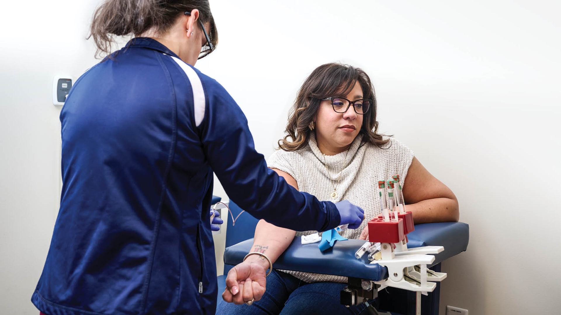 Illeana Casiano-Vazquez sits with her arm out as she has blood drawn