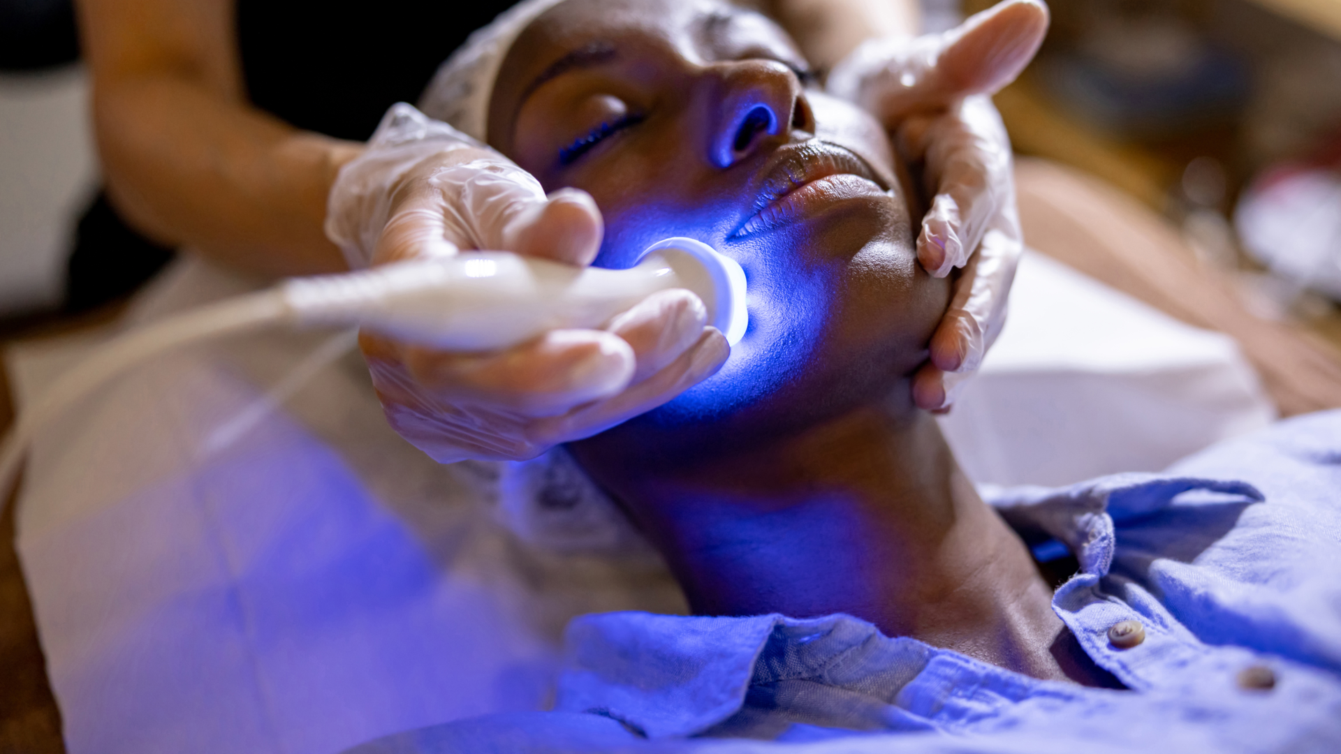 African American woman at the spa getting a rejuvenation treatment on her face using ultrasound and light therapy.