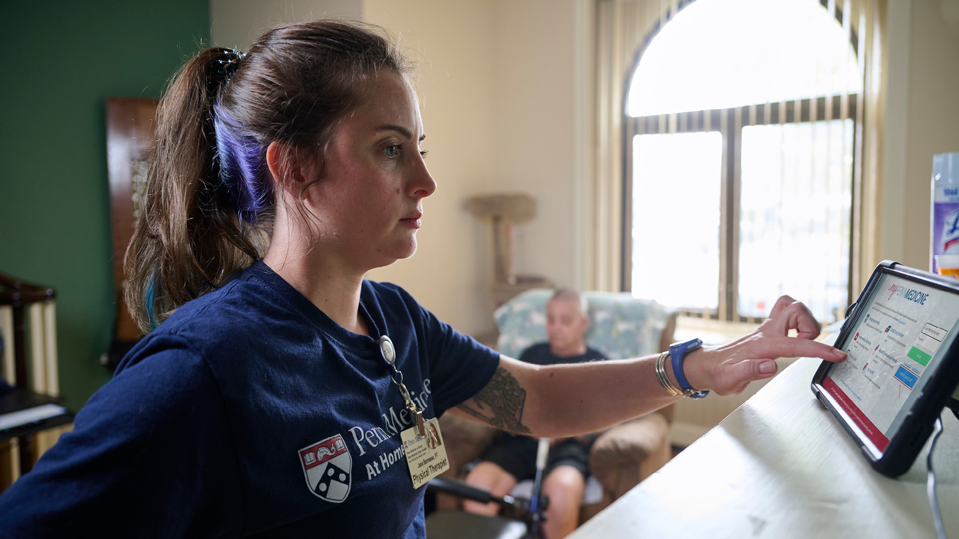 Physical therapist Jana Barmasse reviews information on a tablet that Mike Desalis uses to report health updates to his care team