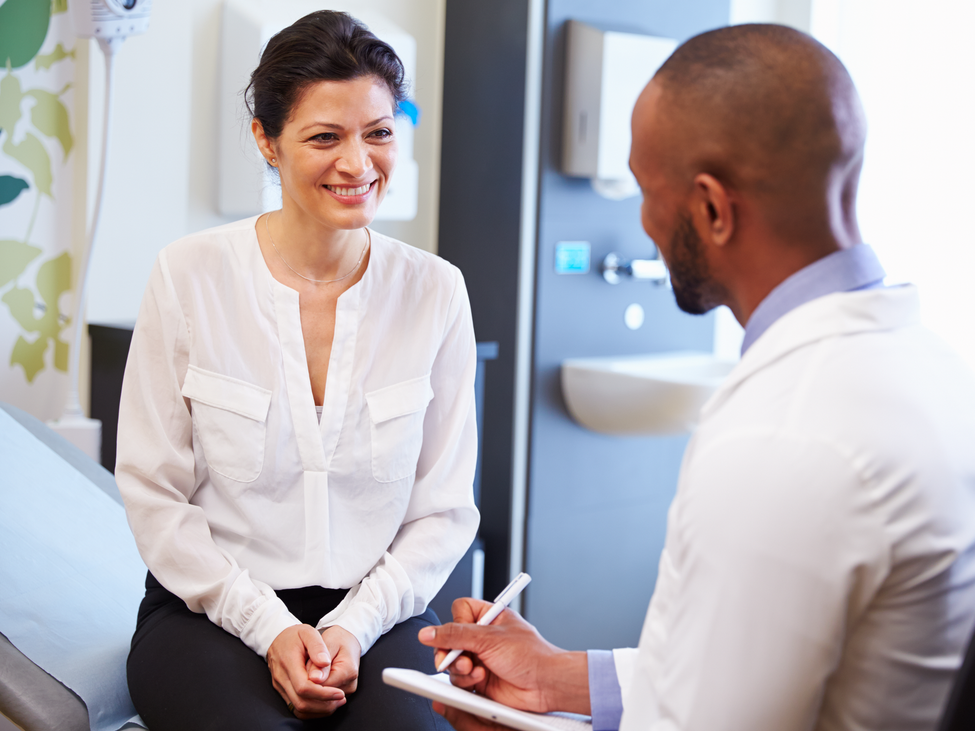 Female Patient And Doctor Have Consultation In Hospital Room