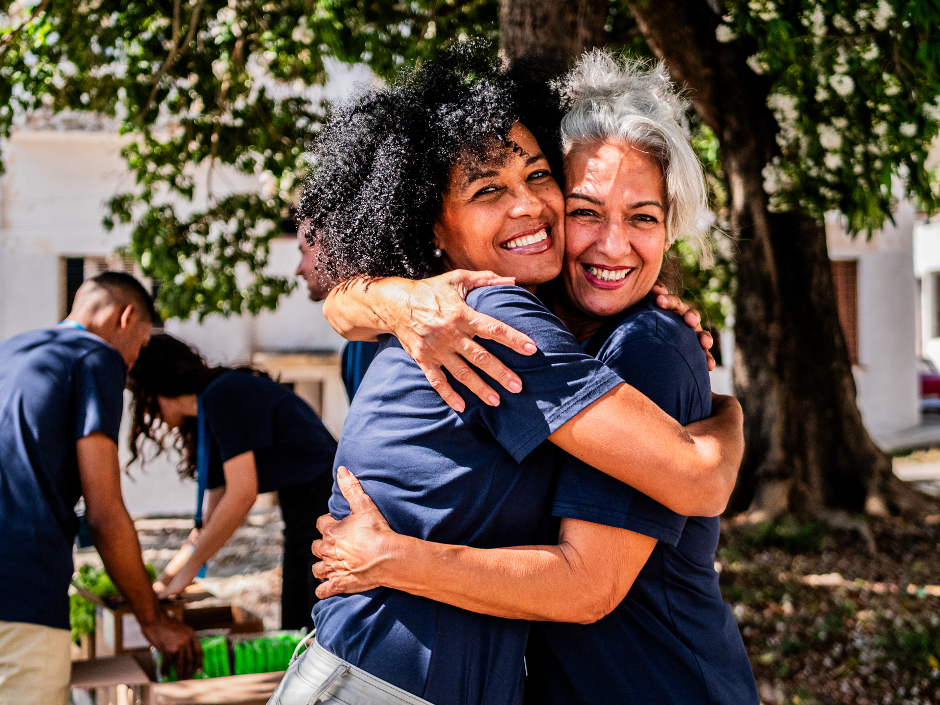 Portrait of volunteer friends embraced in outdoor settings.