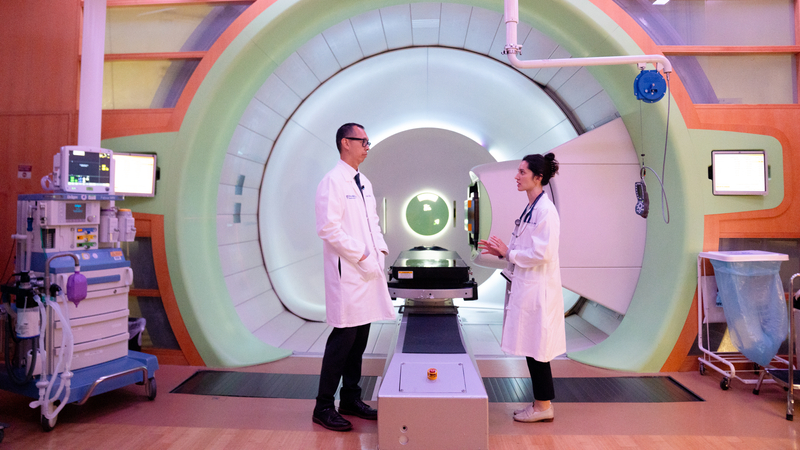 Alexander Lin and an advanced practice provider standing in front of a proton treatment room