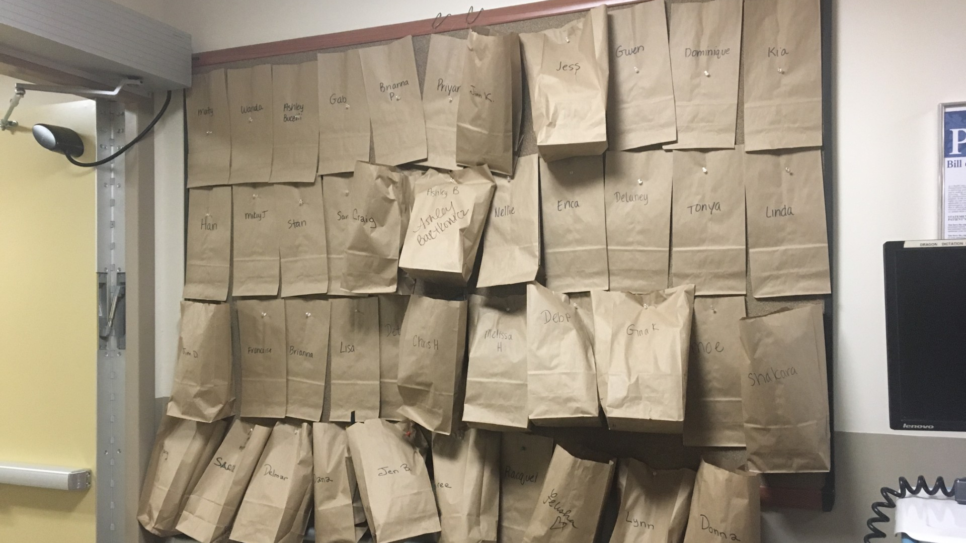 Brown paper bags containing each nurse’s N95 respirator hang on a bulletin board in a unit at Penn Presbyterian Medical Center