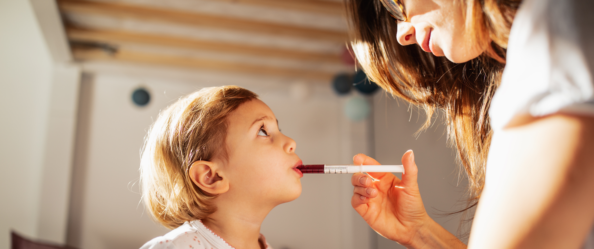 Mother giving child medication out of syringe