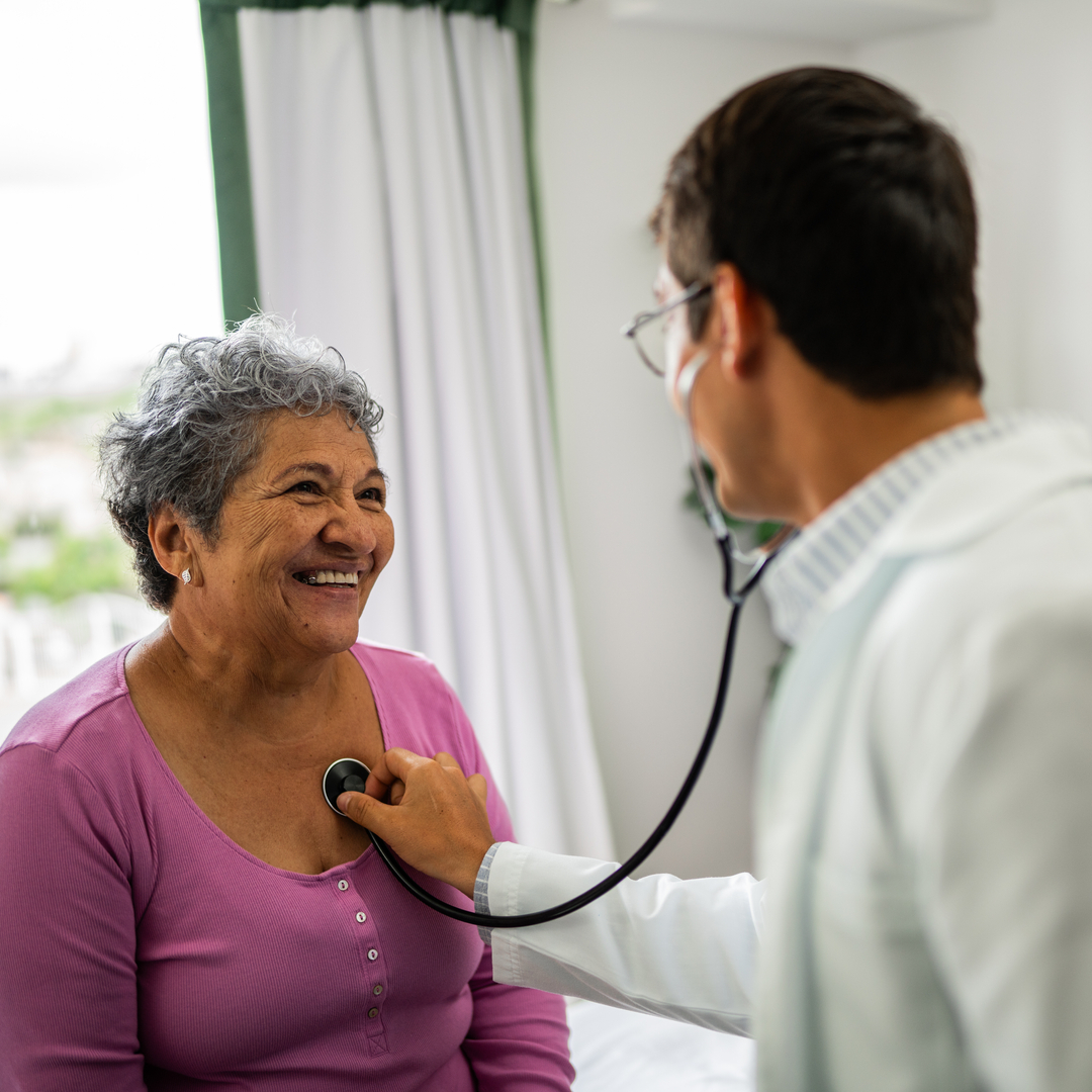 Doctor listening senior patient woman's heartbeat during consultation at hospital