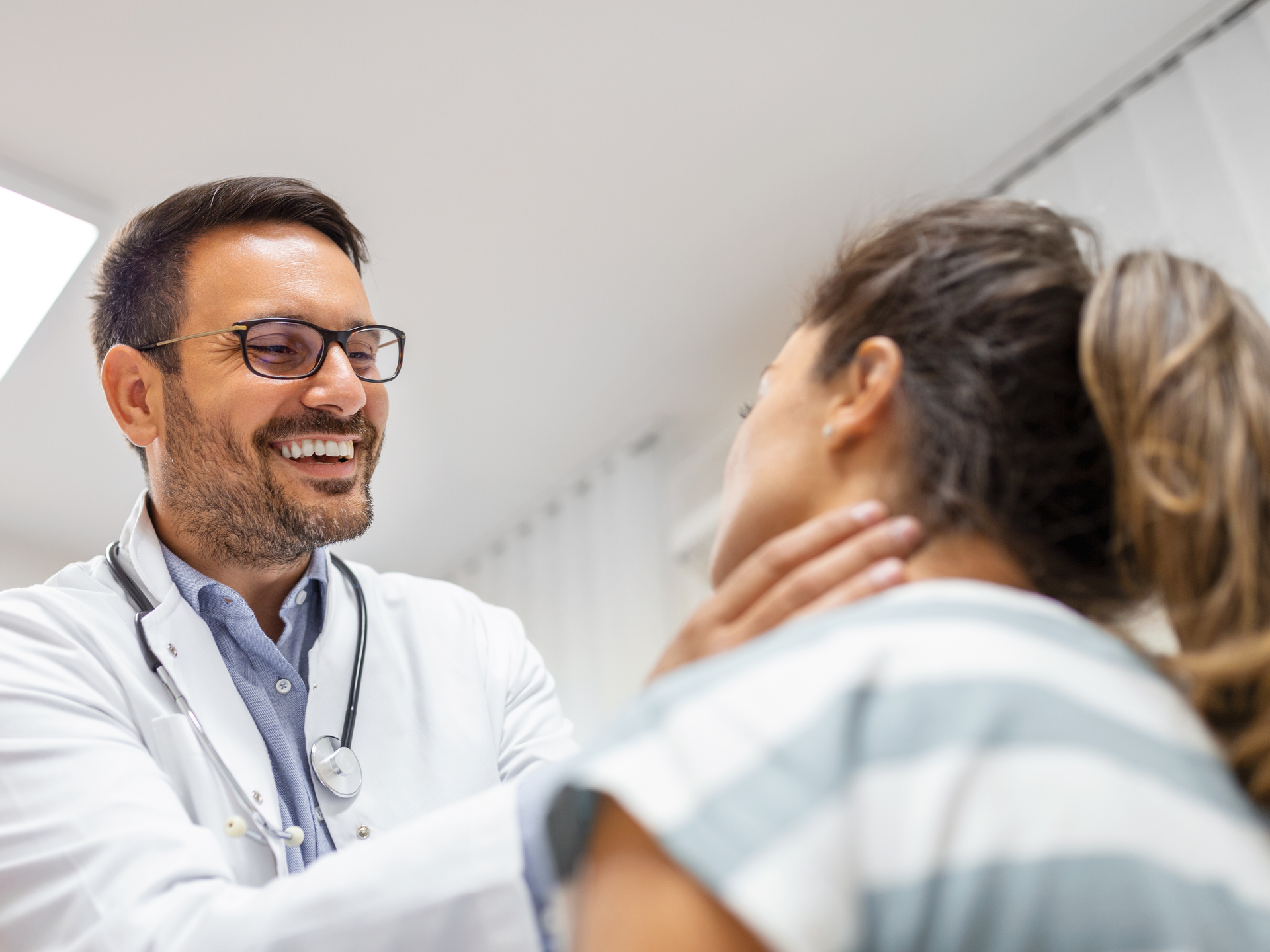 Endocrinologist examining throat of young woman in clinic. Thyroid gland test 