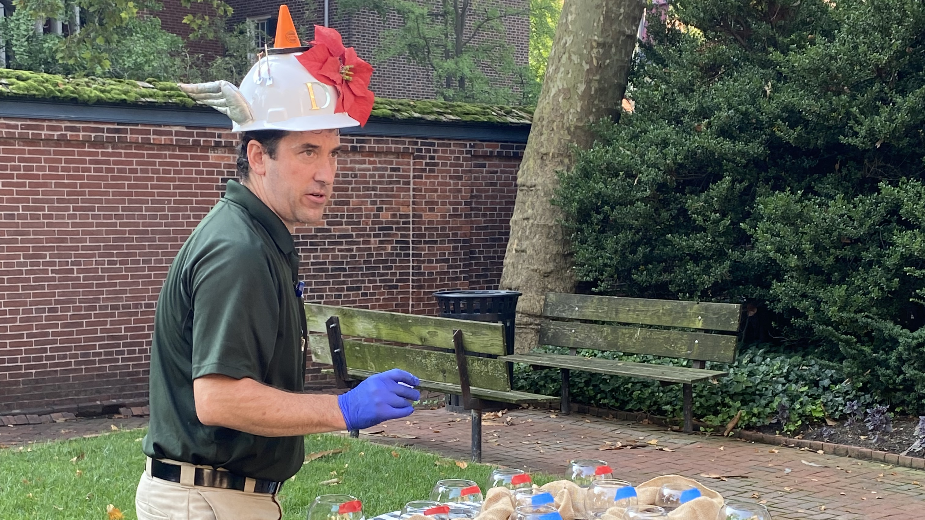Dan Bangert stands next to a table with fish bowls and wears a white construction hat