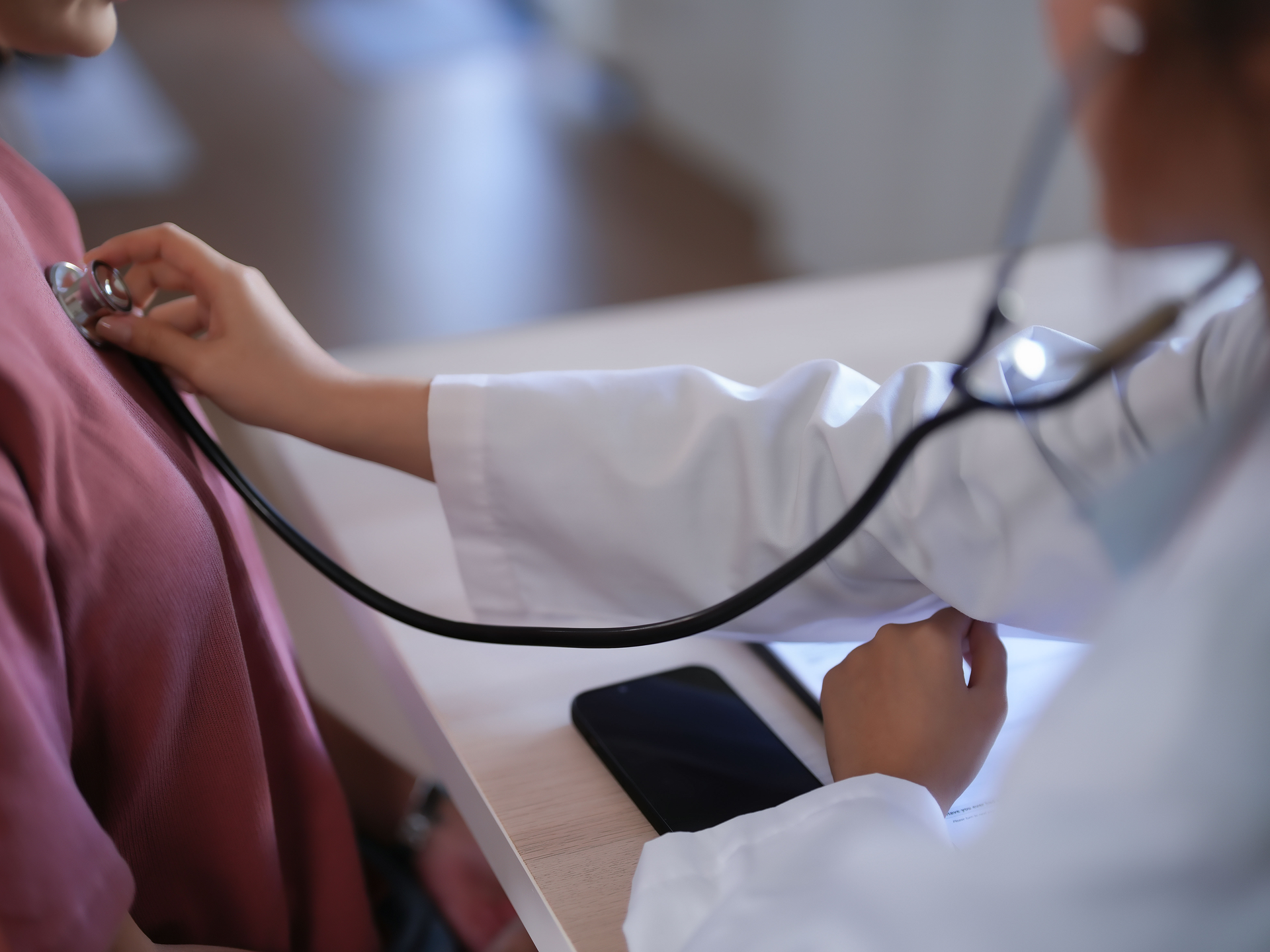 Doctor using stethoscope on patient's chest