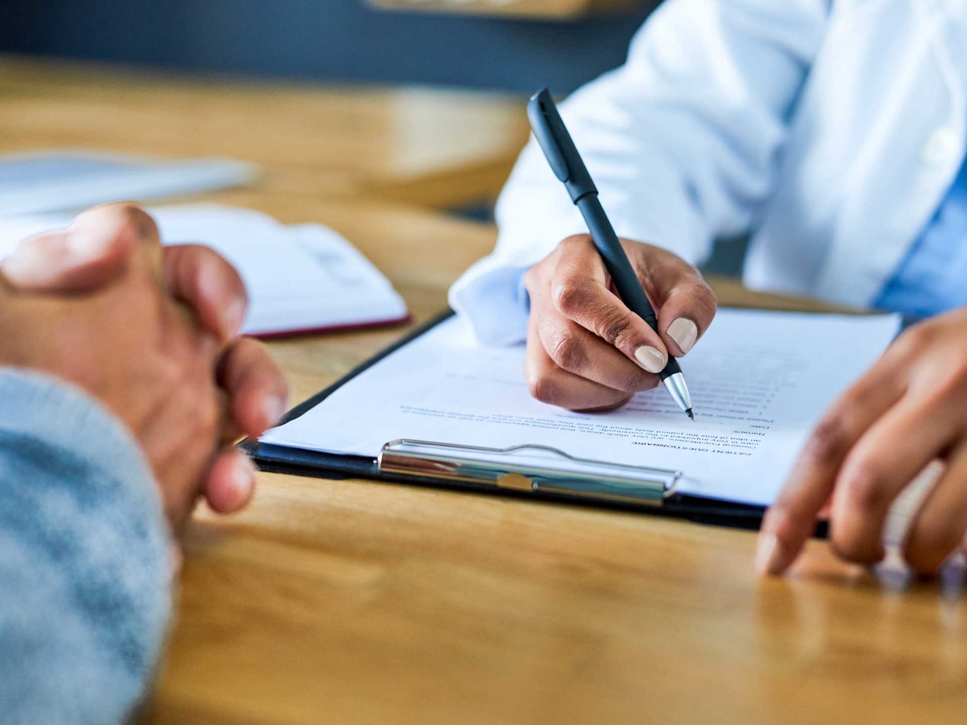 Closeup shot of a doctor writing notes during a consultation with a patient