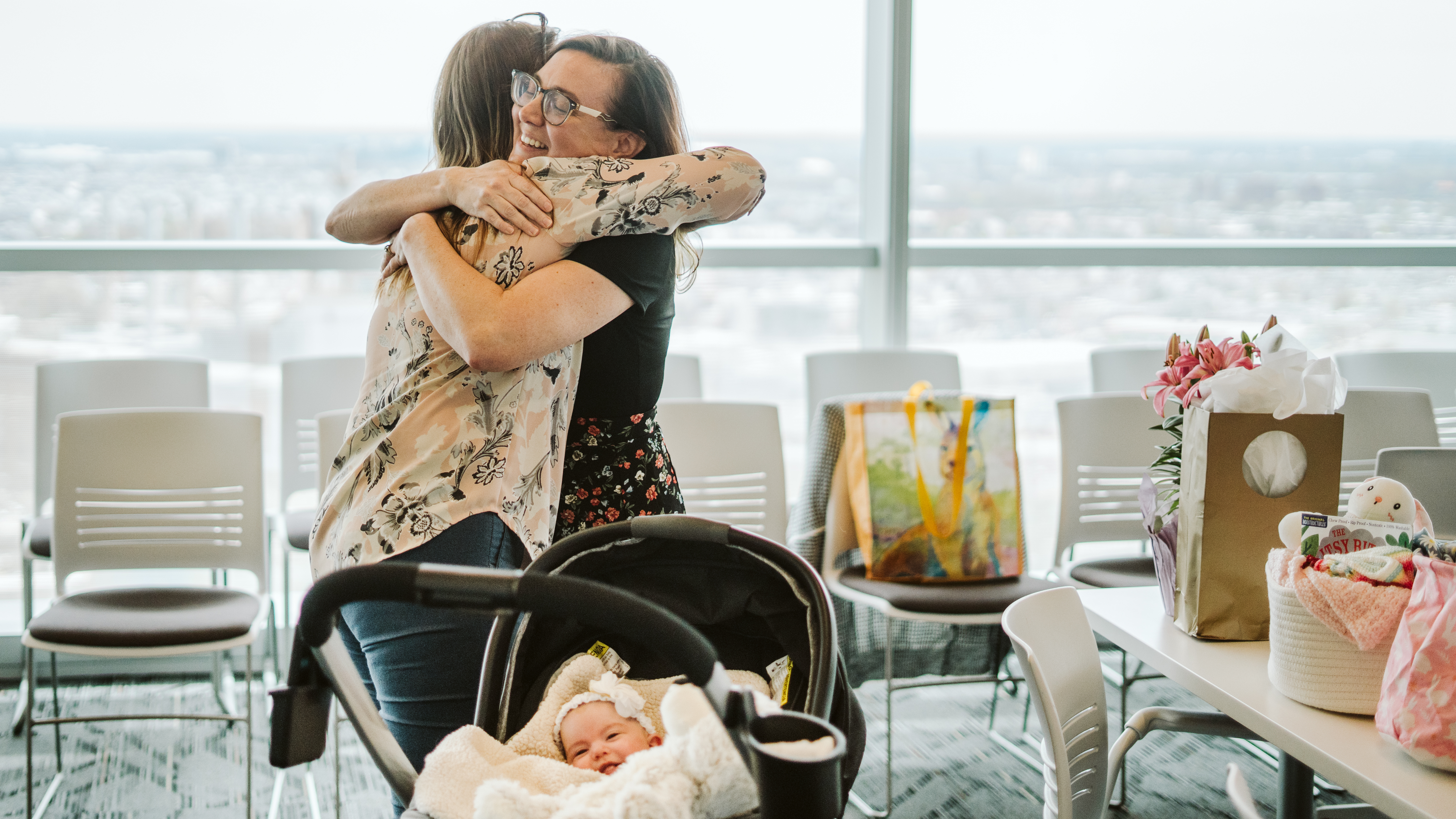 Ashley Christman and Justyna Ruiz embrace, with baby Adrianna in the stroller in the foreground