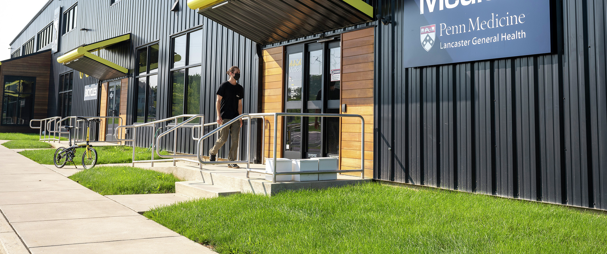 A person walks toward the door of a large modern building with signage that says Rock Medical, Penn Medicine Lancaster General Health
