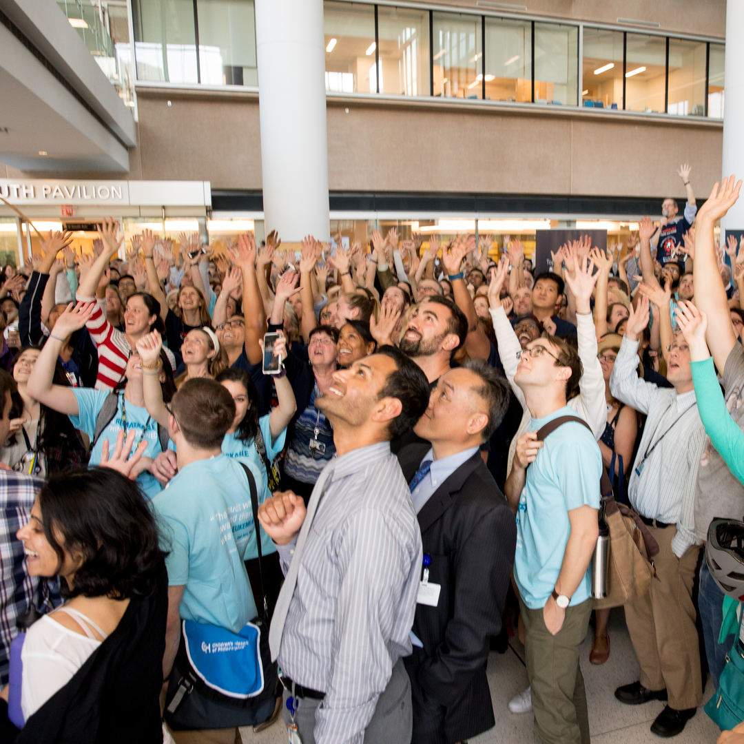 A crowd of people looks up, waving
