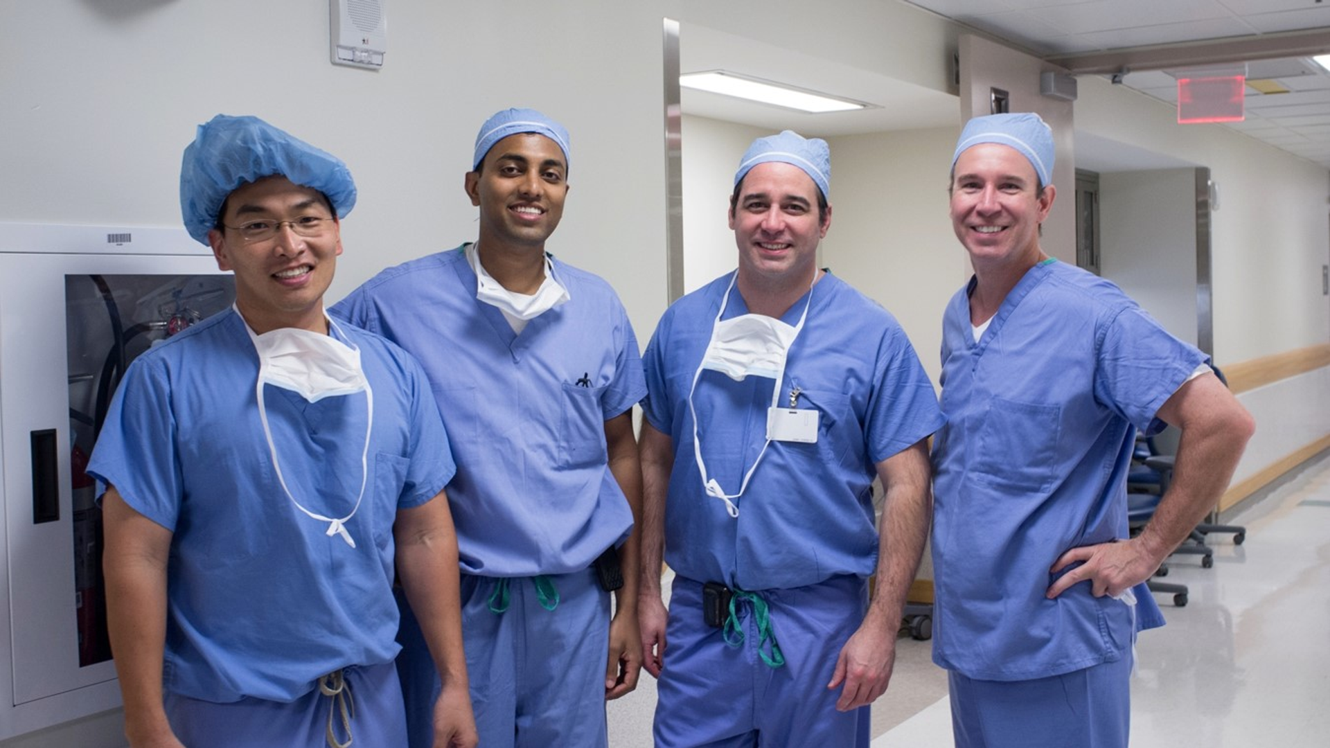 Surgeons Drs. Lee, Adappa, Palmer, and Storm stand in surgical scrubs outside an operating room