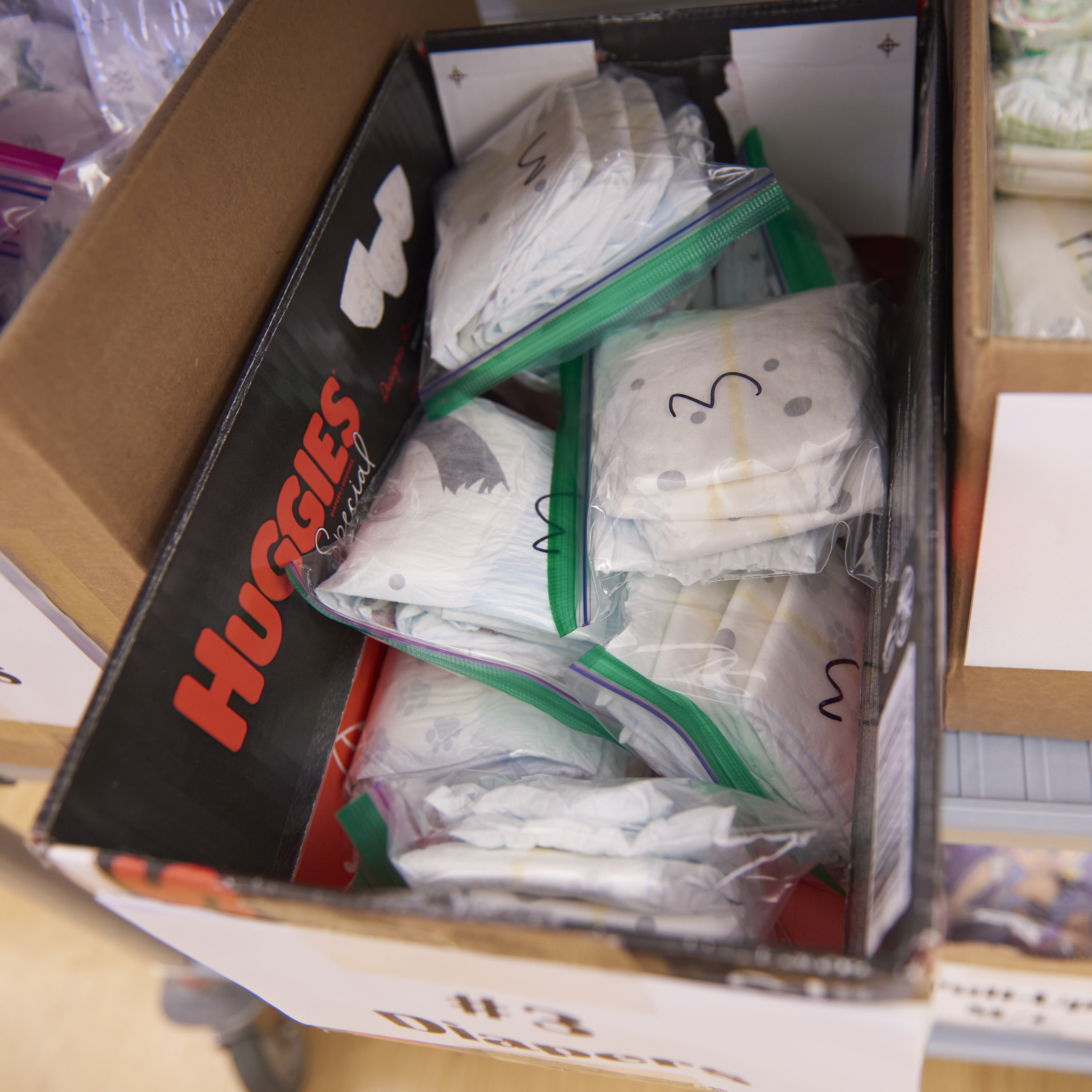 A row of boxes is filled with new diapers of different sizes