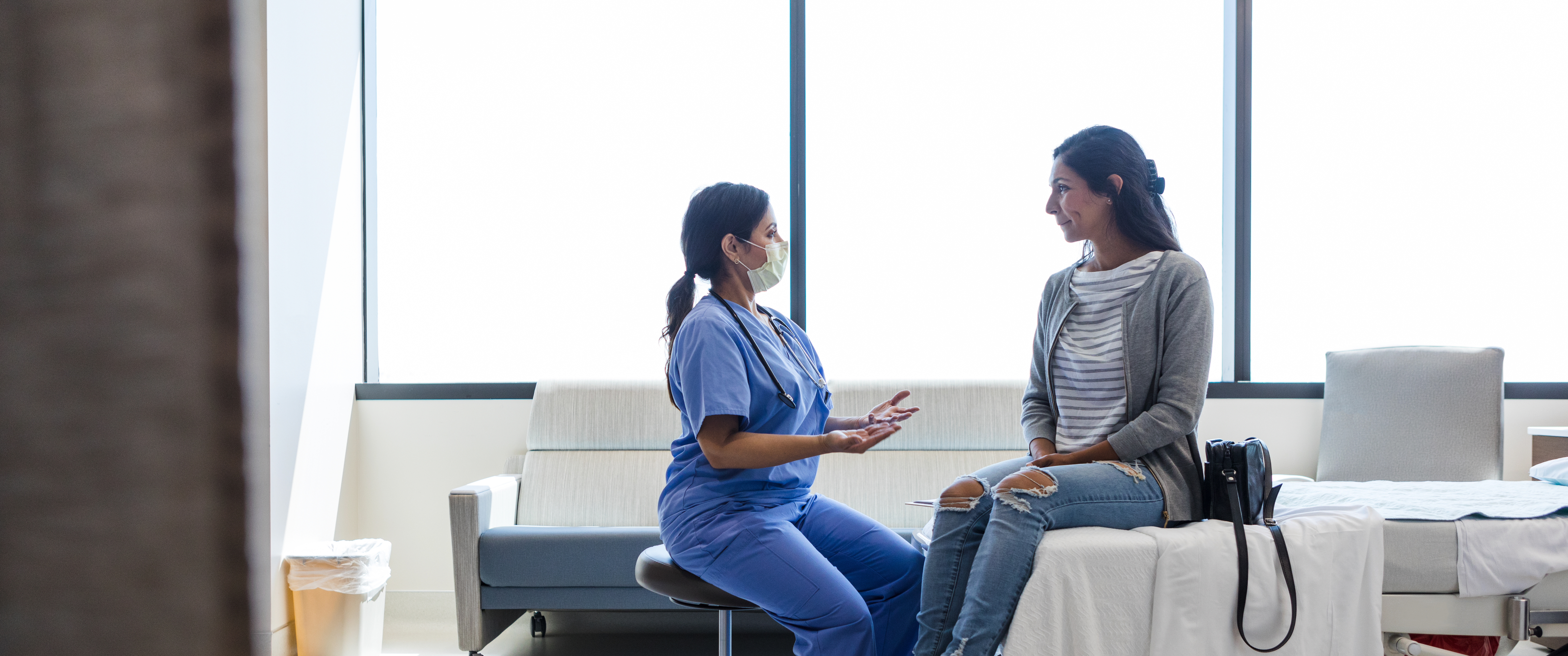 Doctor talks to her female patient in ER examination room