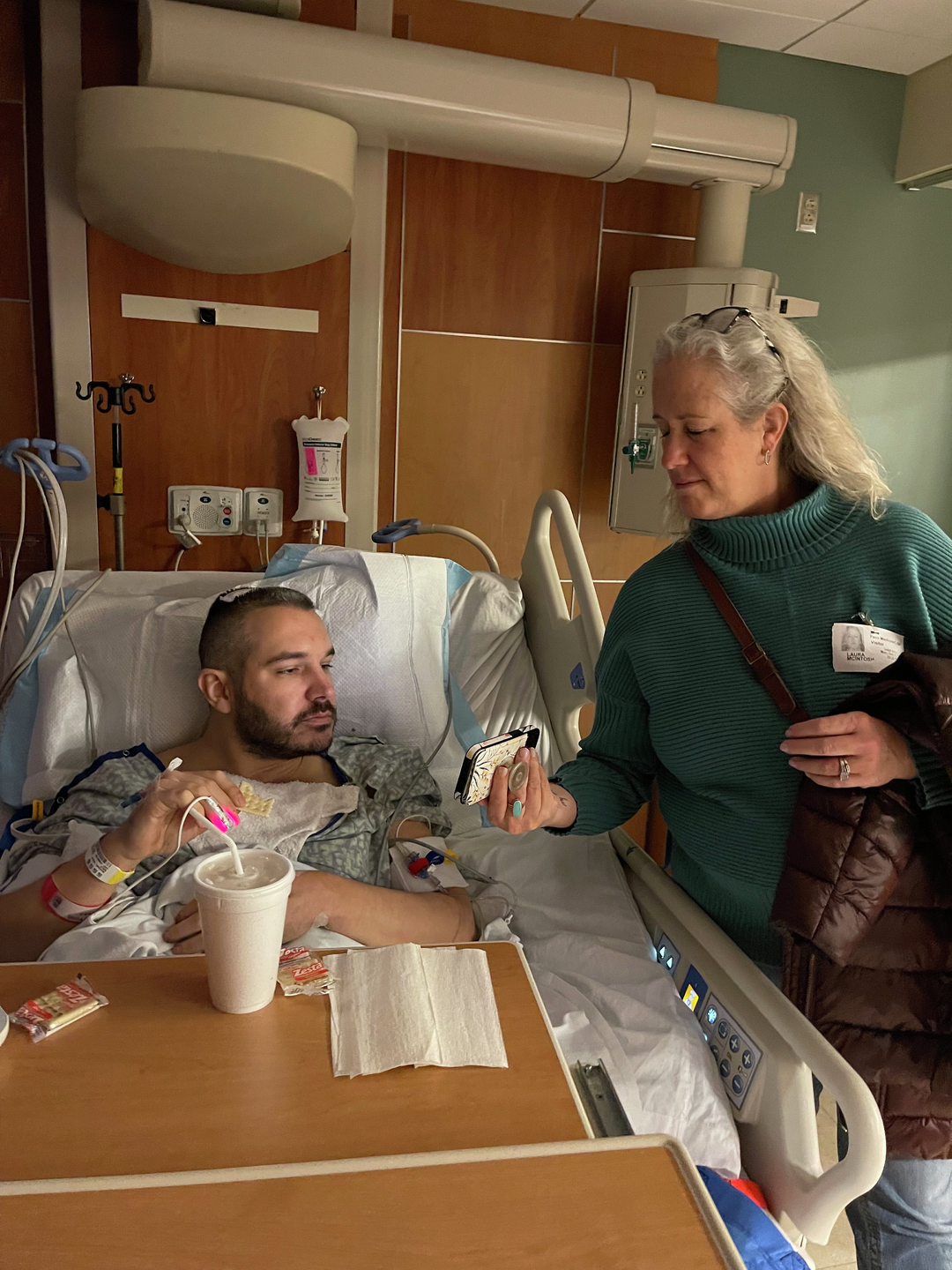 Tanner McIntosh, in a hospital bed post-surgery, with his mom standing next to him in the room