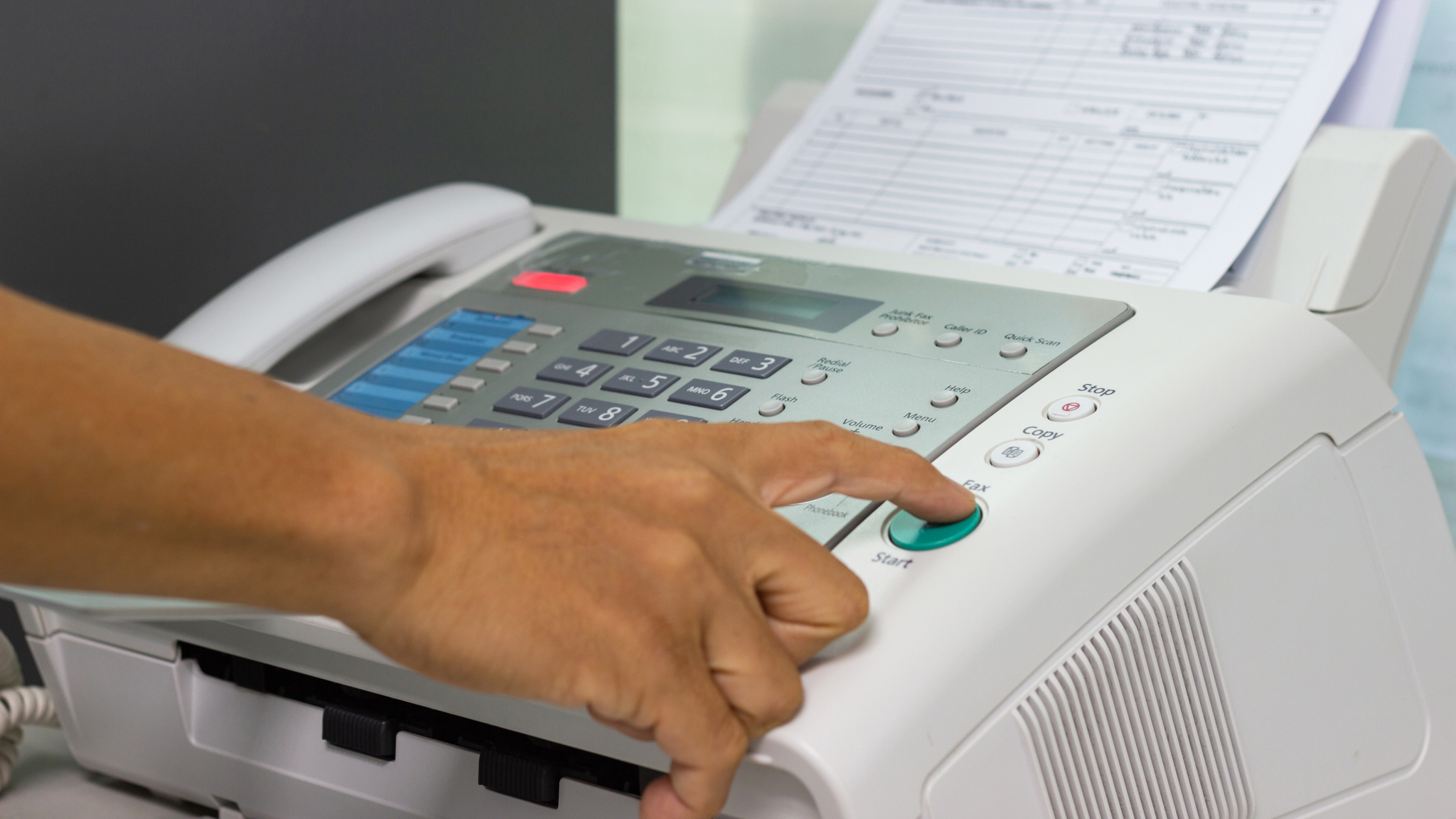 Hand pressing a button on a fax machine