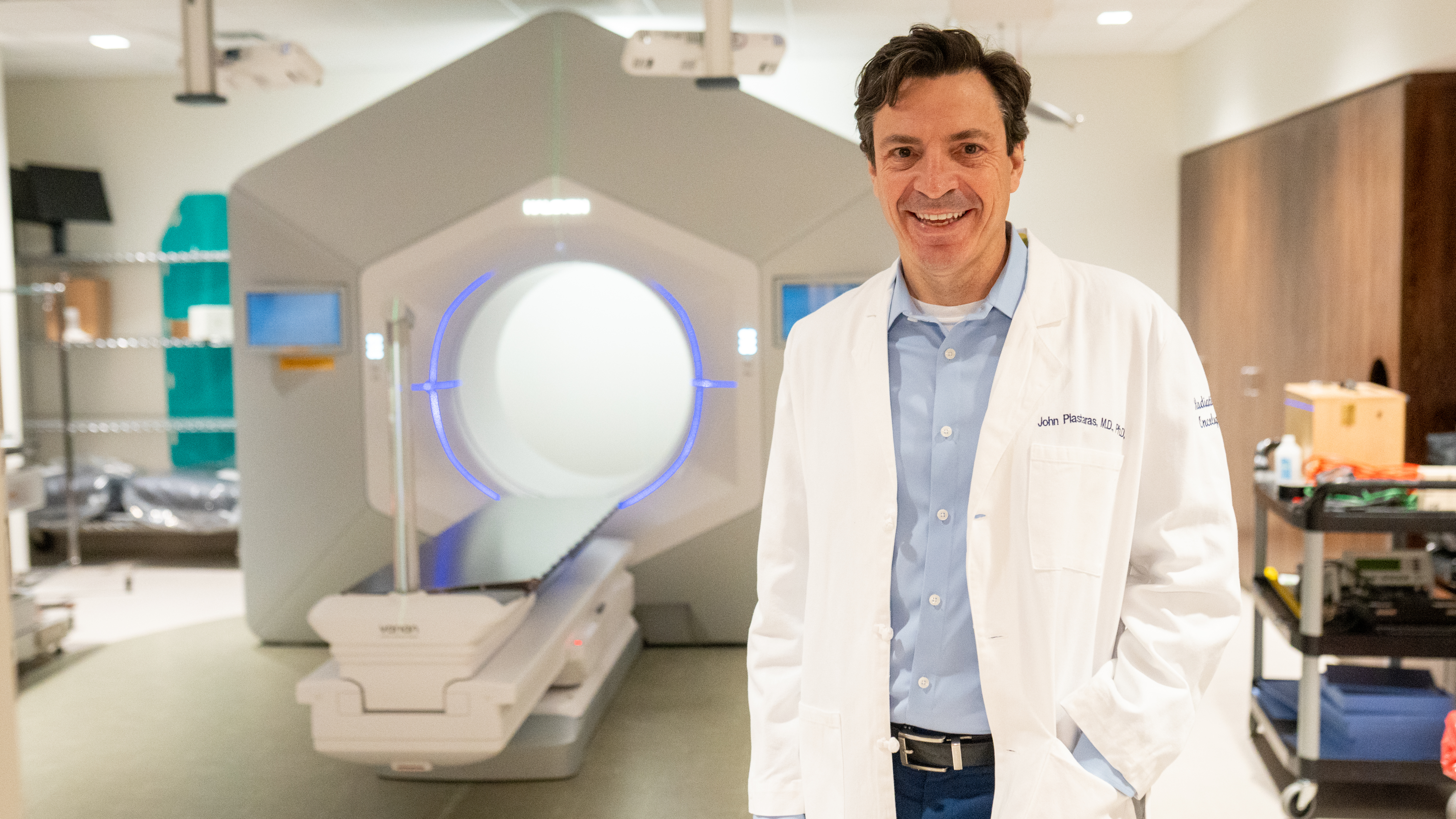 John Plastaras standing in front of a radiation therapy device
