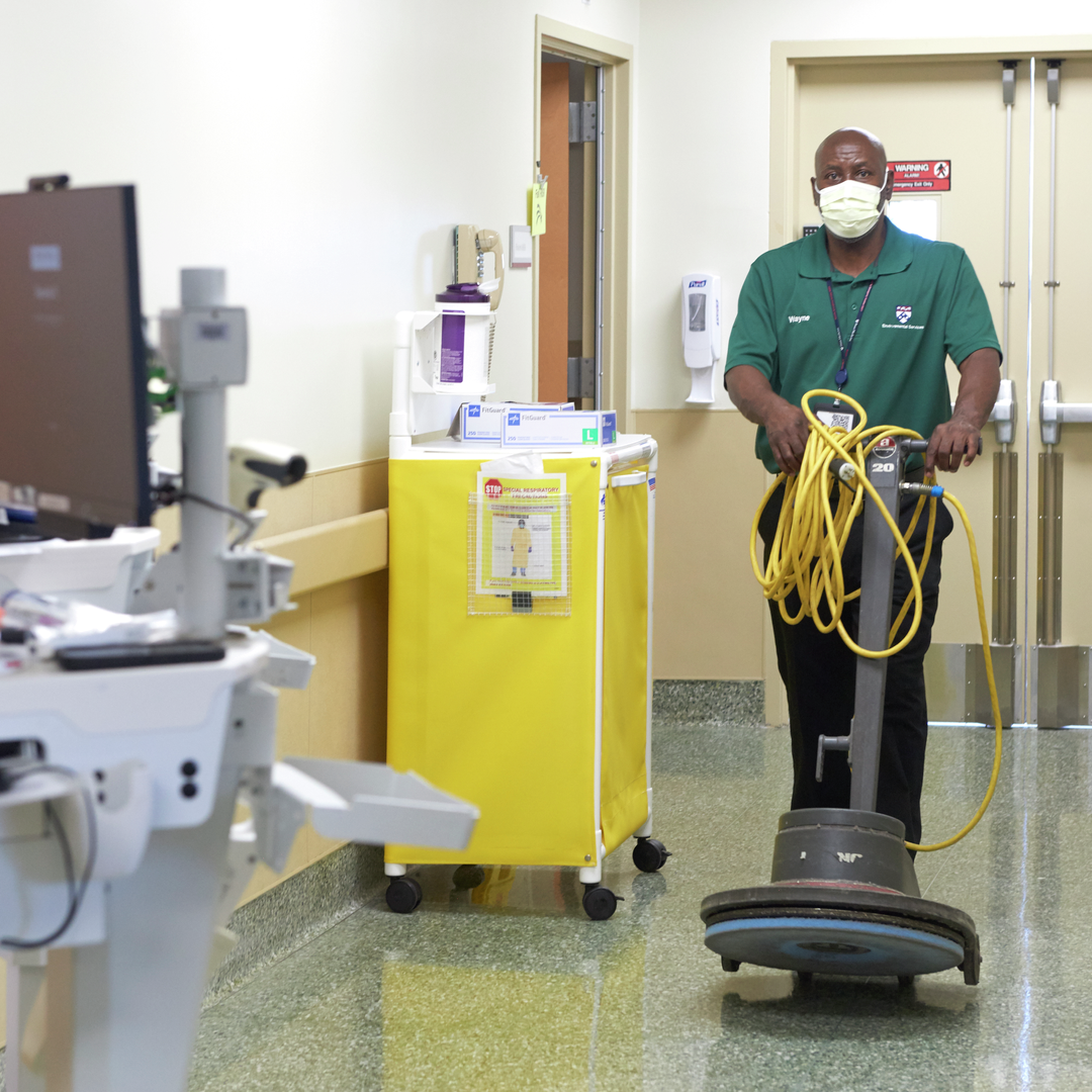 An environmental services worker rolls a floor polisher through the hospital hallway
