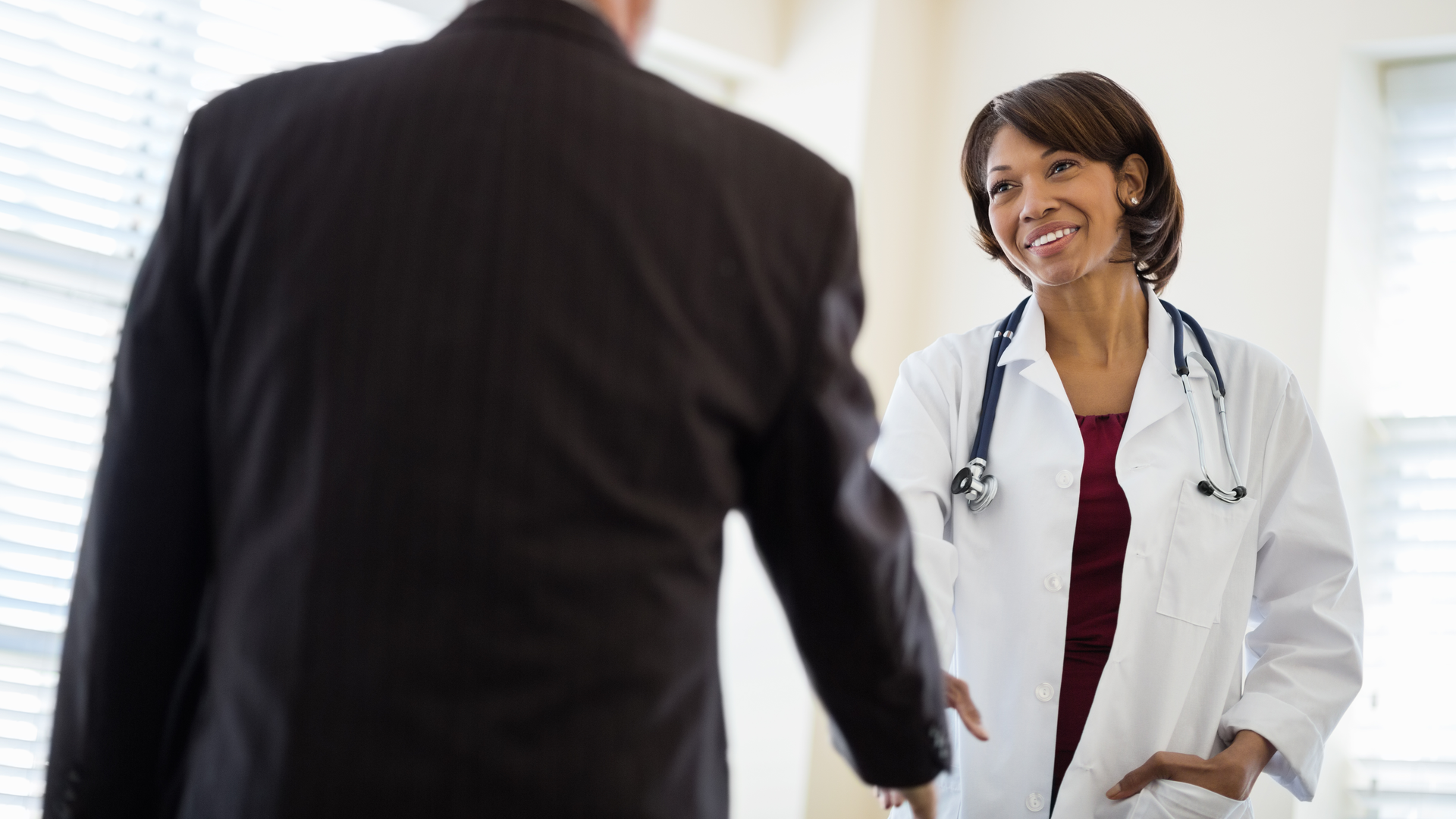 Female doctor greeting senior businessman in clinic