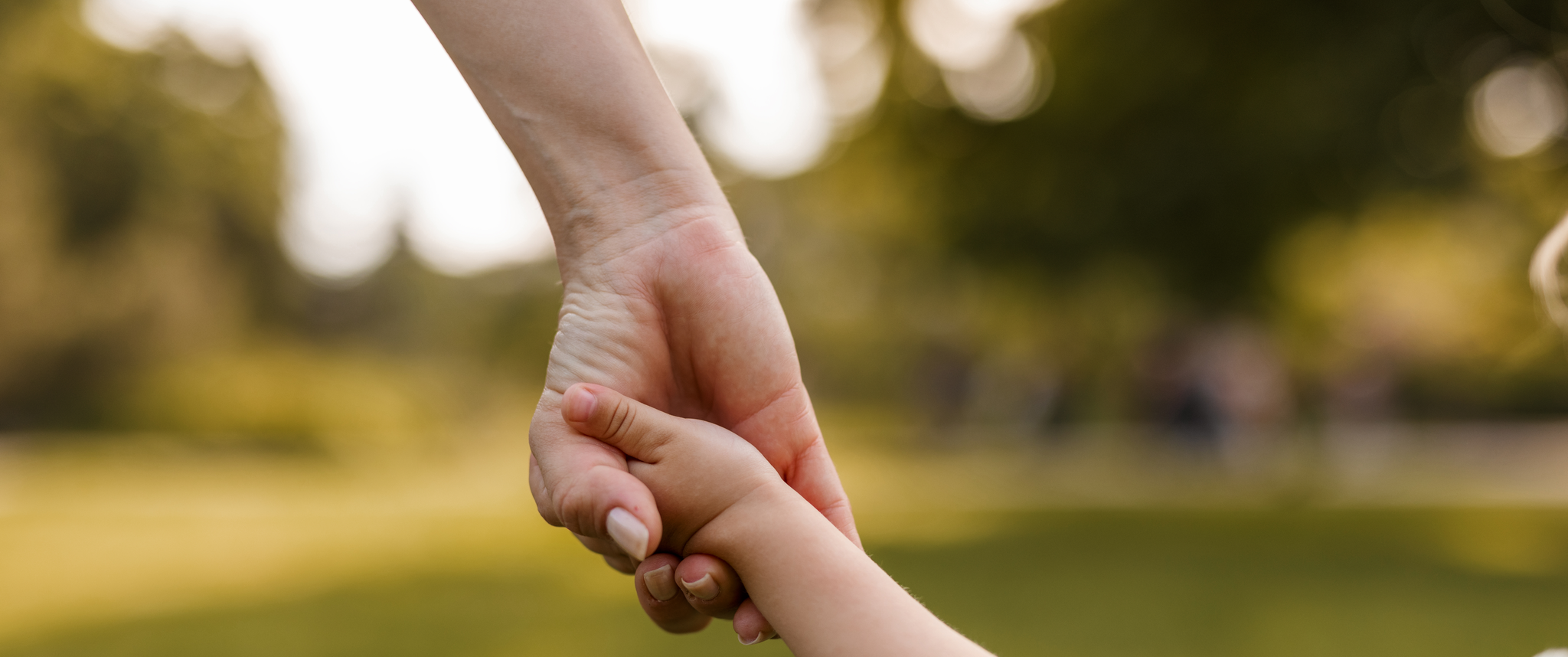 Mother holding child's hand outdoors