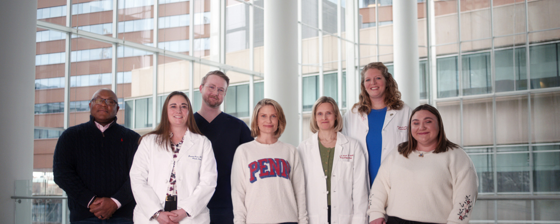 A group photo including Kate Korson in the center wearing a Penn sweatshirt, surrounded by people involved with her cancer care
