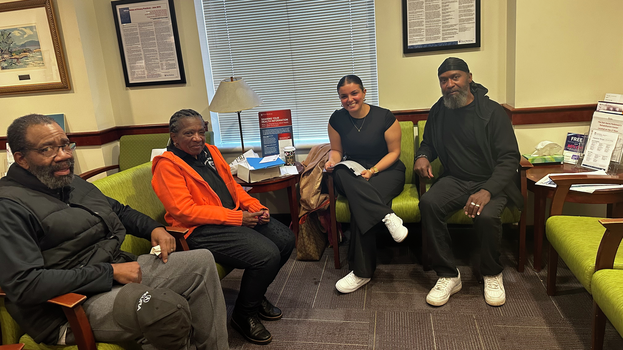 Amanda Cruz, second from right, sits with three patients of the Parkinson’s Support Group in a meeting space.
