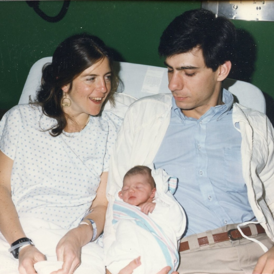 A young Jean Bennett in a hospital bed with Al Maguire leaning in, holding their newborn baby