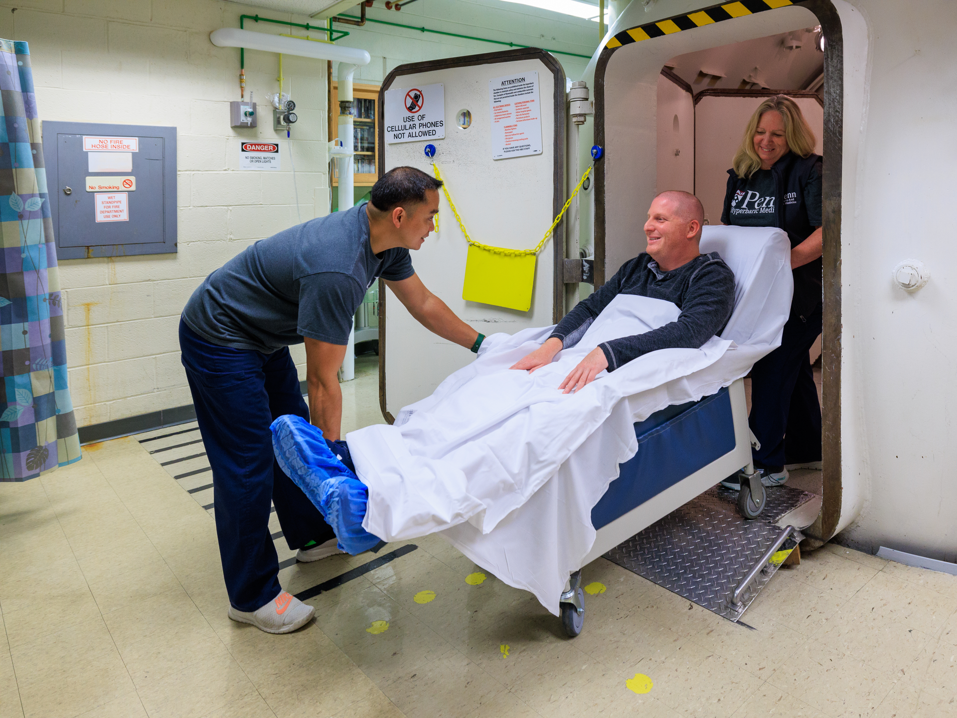 Patient being wheeled into hyperbaric chamber by Penn Medicine staff