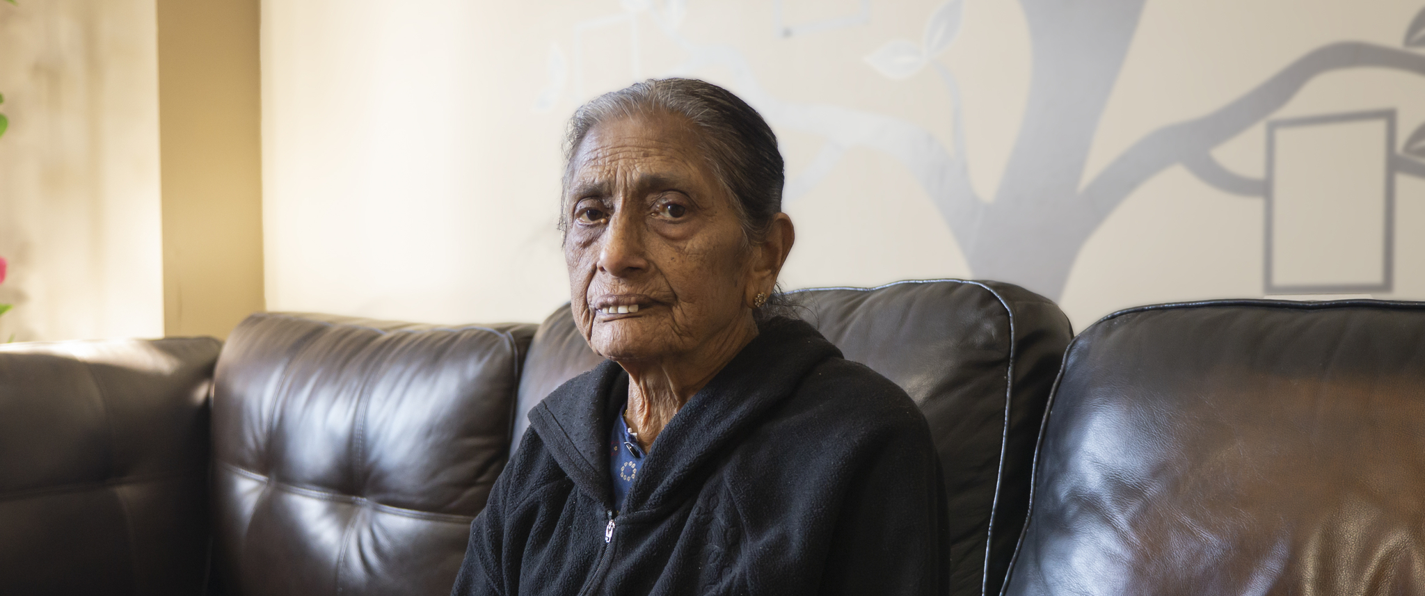 Vilma Patel wearing jacket sitting on sofa