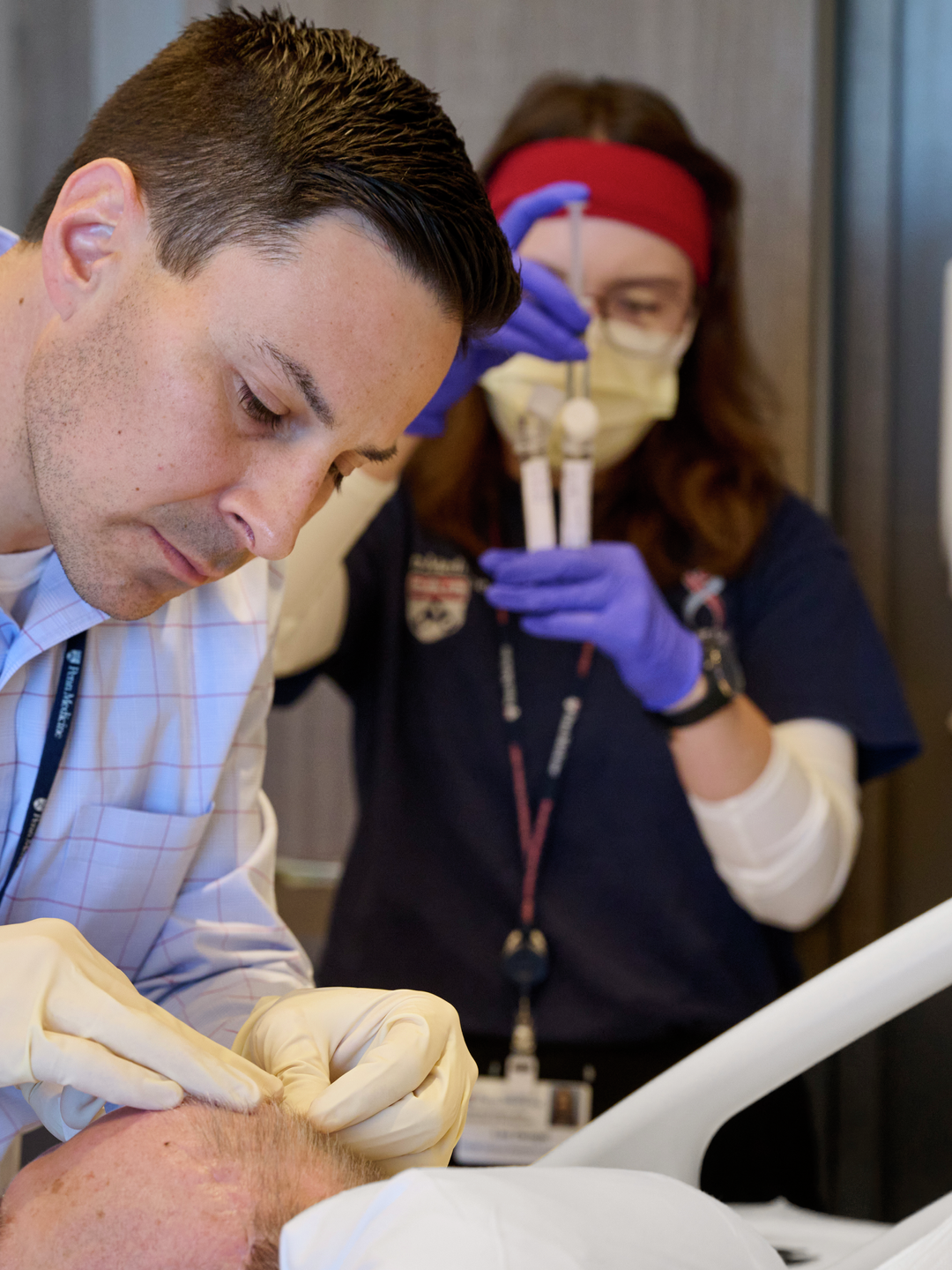 As Dr. Steven Bagley administers CAR T treatment cells, research coordinator Lee Dengel prepares tubes for the collection of research samples