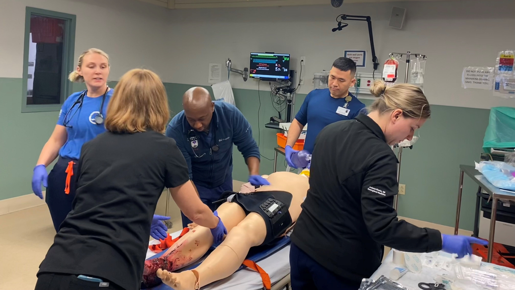 Medical personnel care for a manikin with a "bloody" injured leg