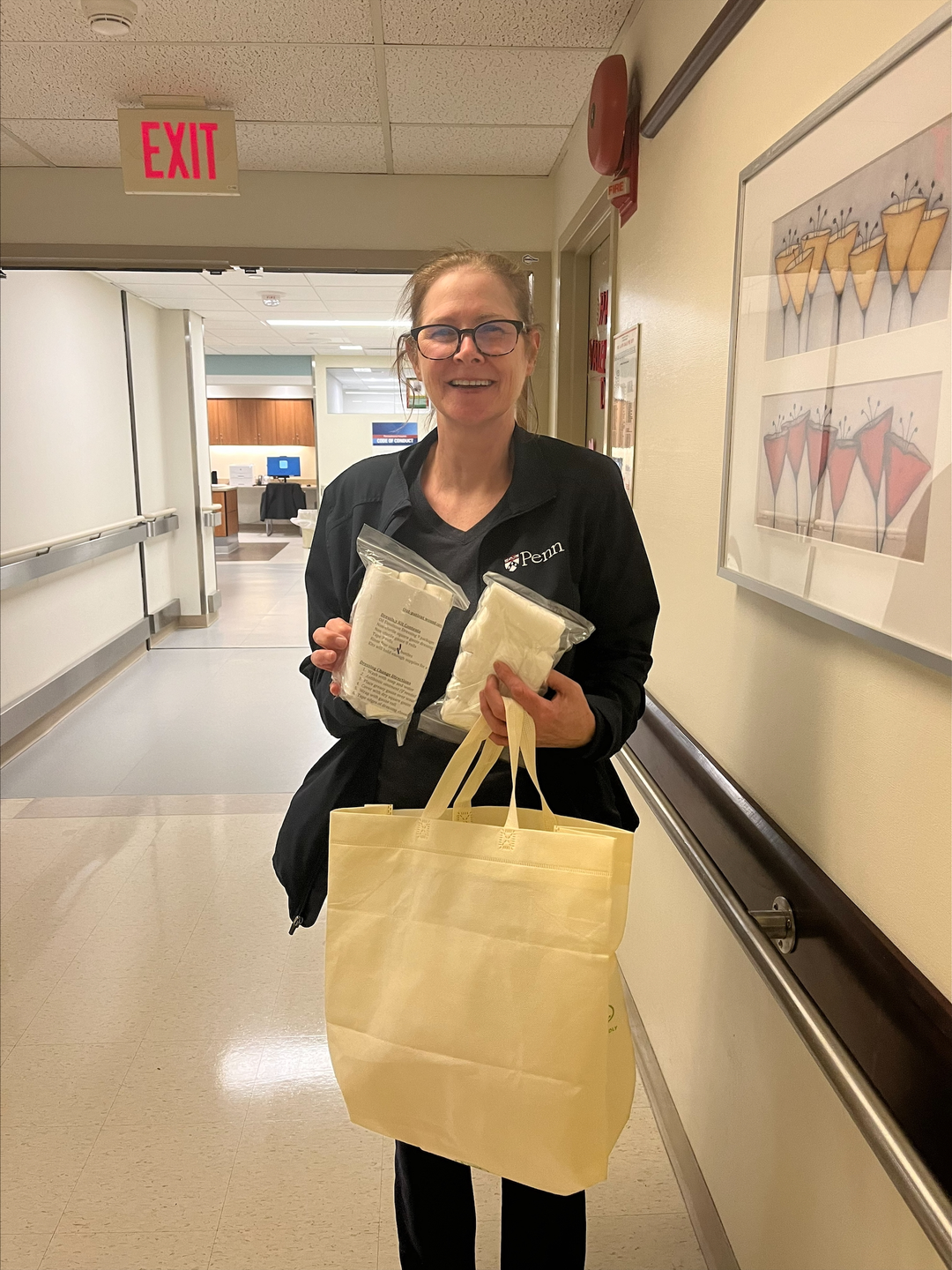 Pattie Lamoreaux standing in a hospital hallway and holding a tote bag and bandages