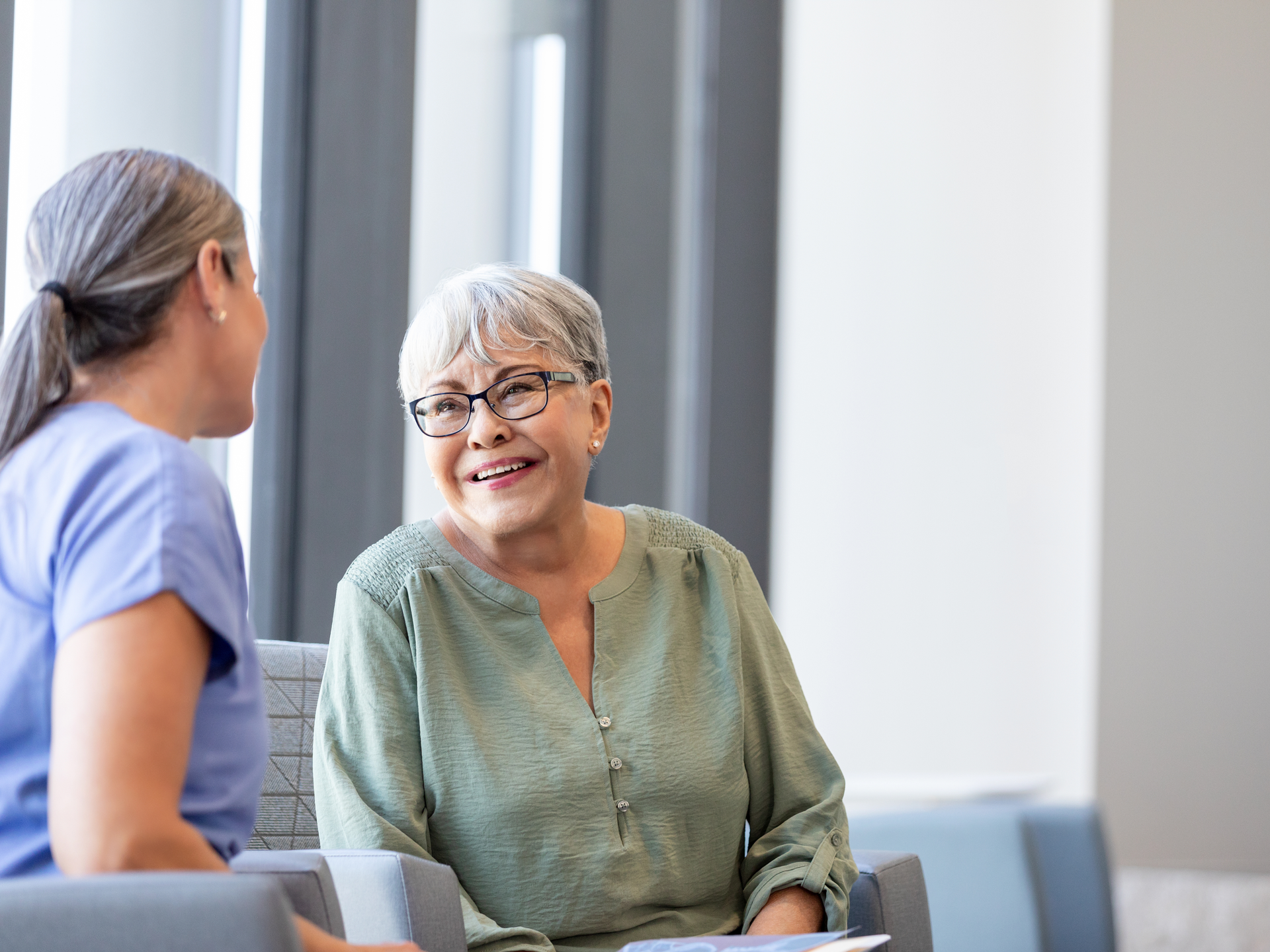 Senior adult woman smiles while talking to nurse navigator