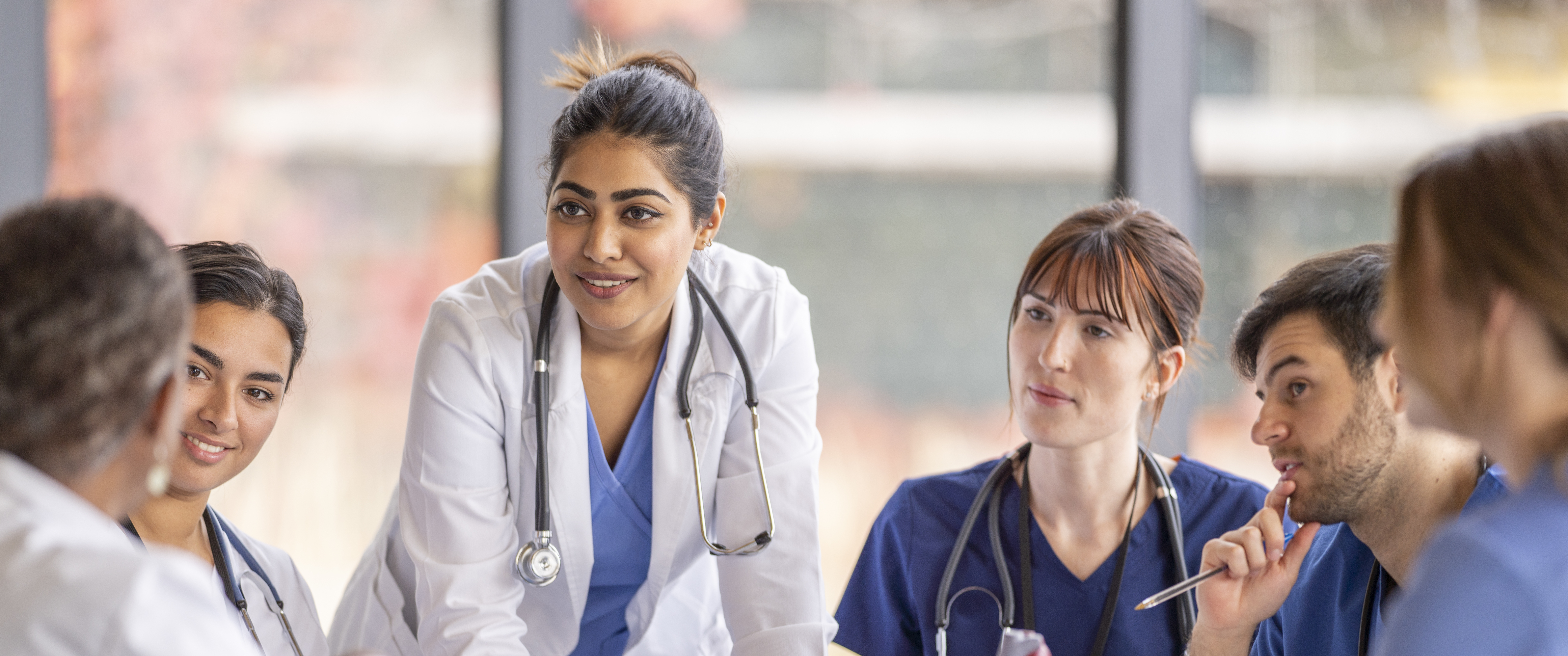 Medical professionals discussing idea around table in meeting room