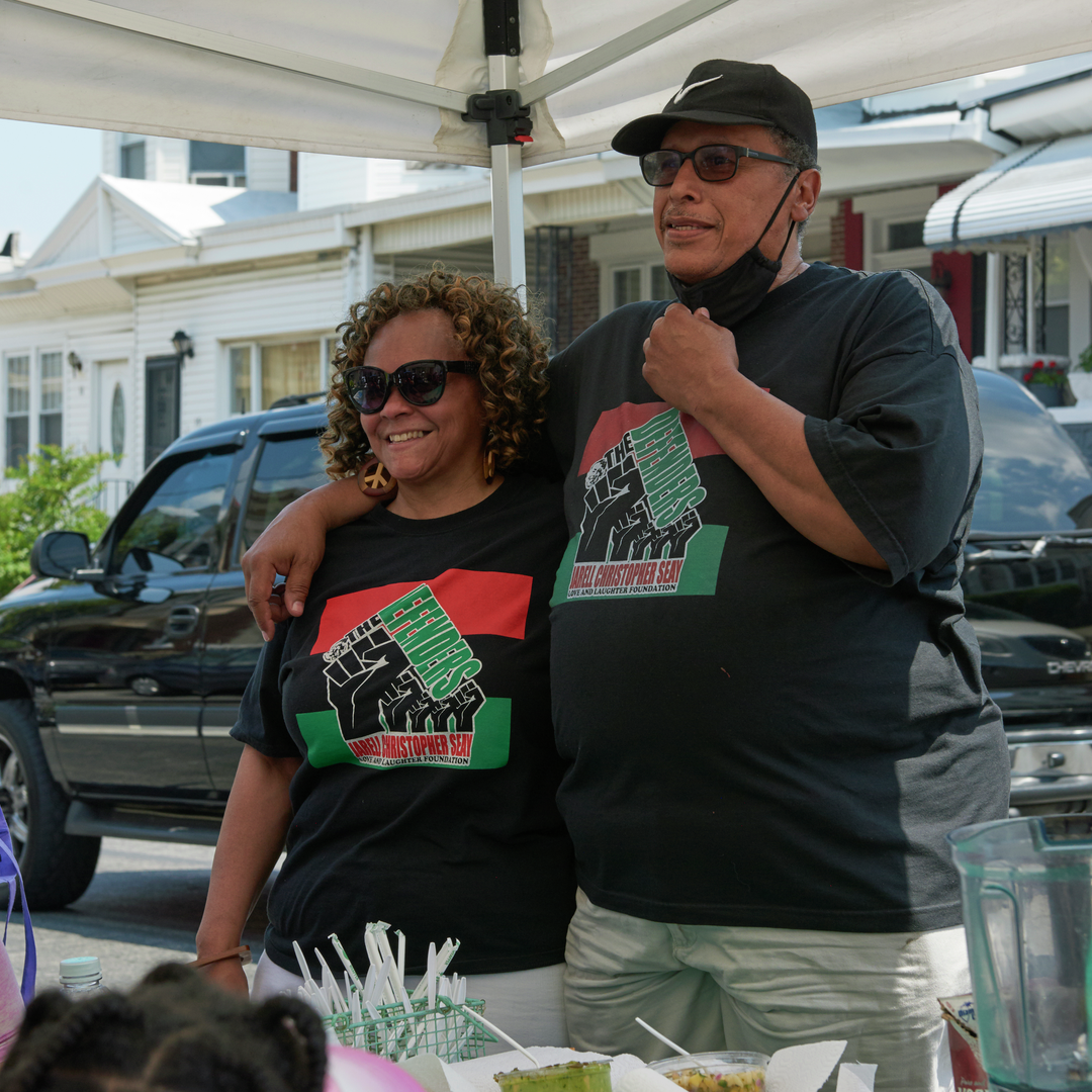 Cherlynne Graham-Seay and Joel Seay stand together outdoors wearing "Defenders" T-shirts
