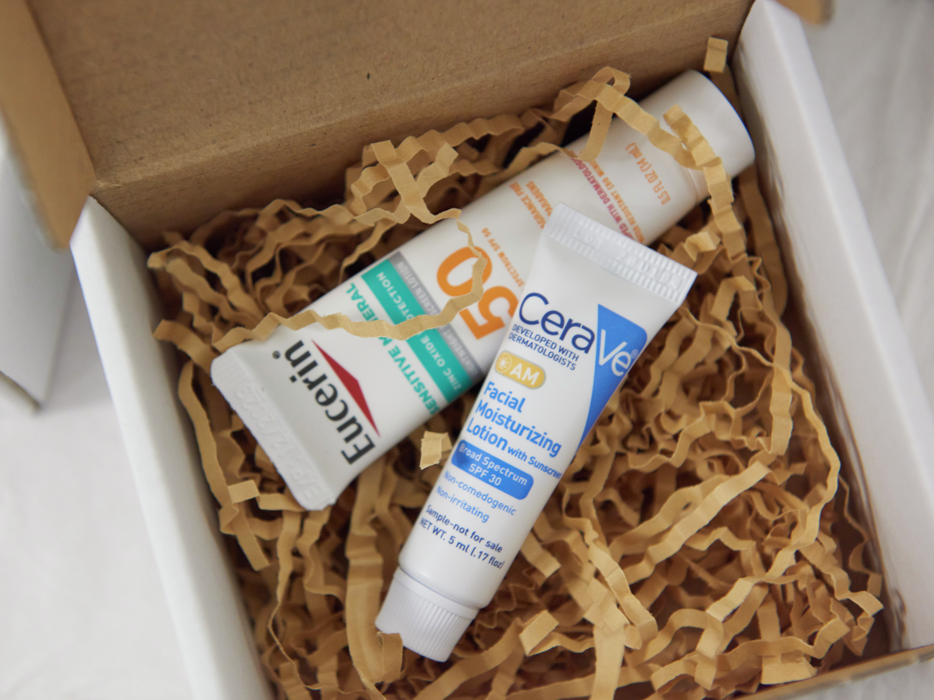 Skin care products inside a box lined with brown paper padding