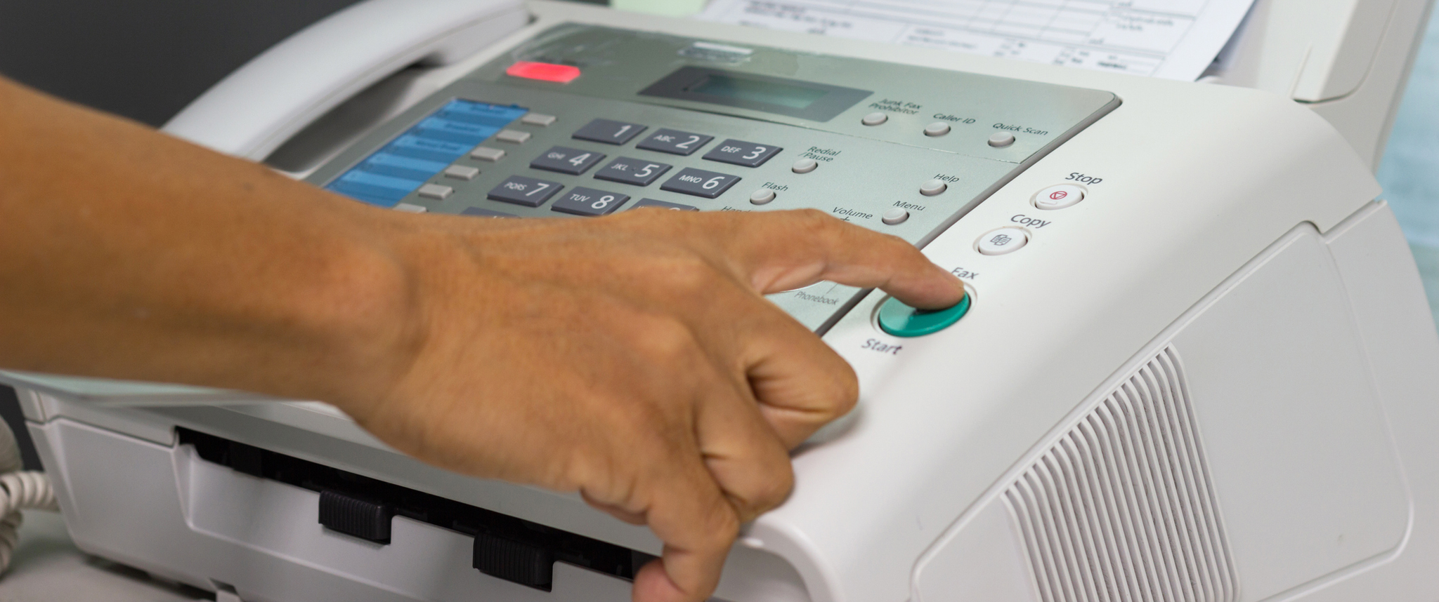 Hand pressing a button on a fax machine