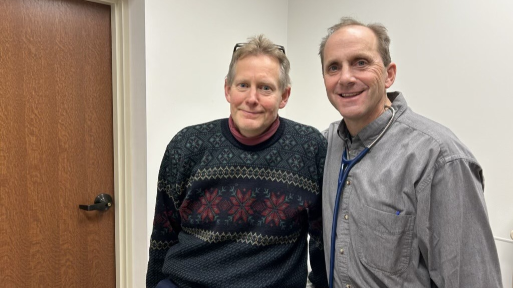 Bill Curtis standing next to James Todd Alderfer in a doctor's office