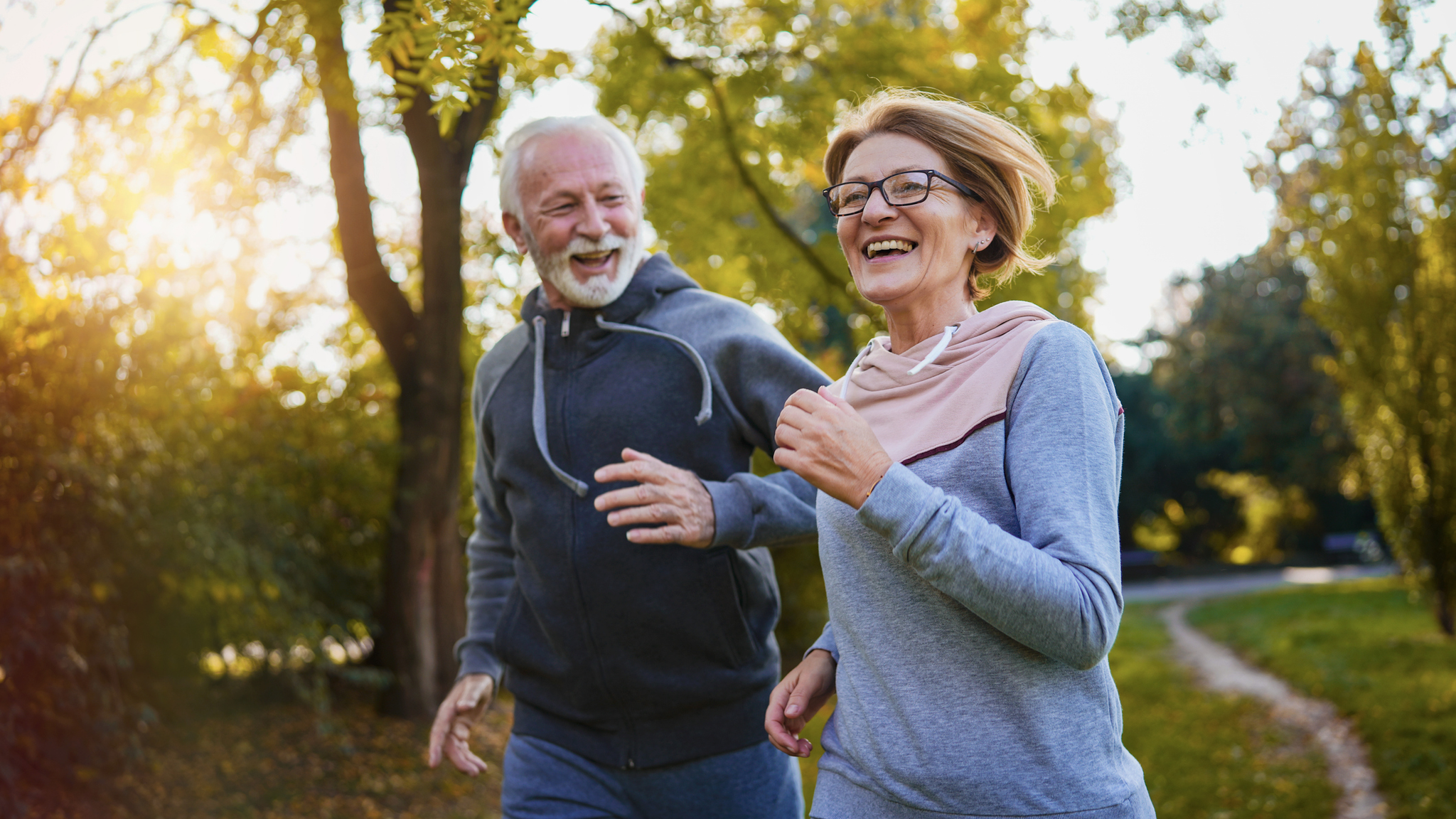 Aging couple running in a park settings.