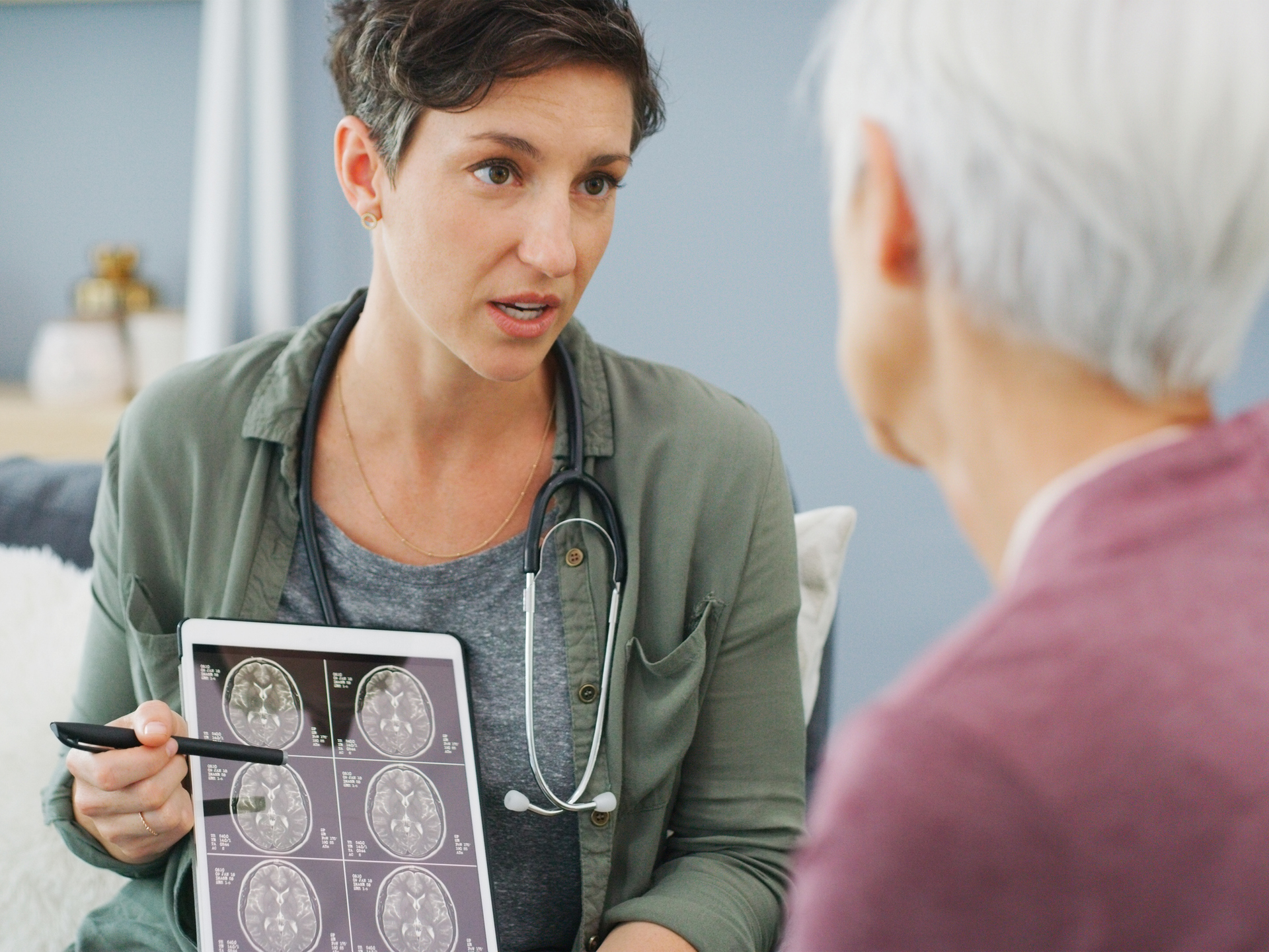 Doctor showing a senior patient her medical results on a tablet while sitting down