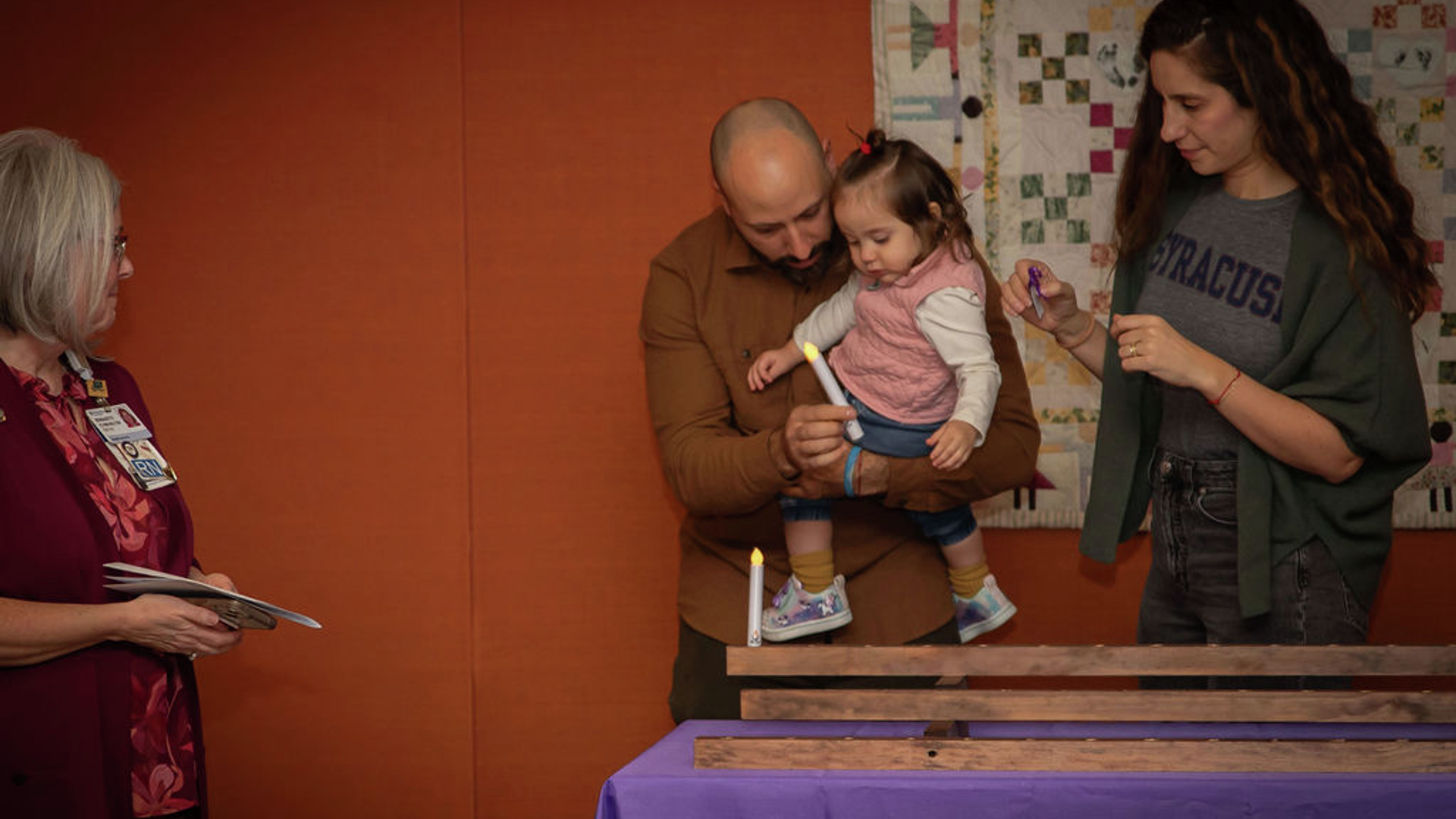 Danny Pennachi, his daughter Adelina, and wife Gina Hererra Pennacchi, place a candle in memory of their son Luciano while Bernadette Flynn-Kelton, outpatient bereavement coordinator at Penn Medicine Princeton Health, looks on.