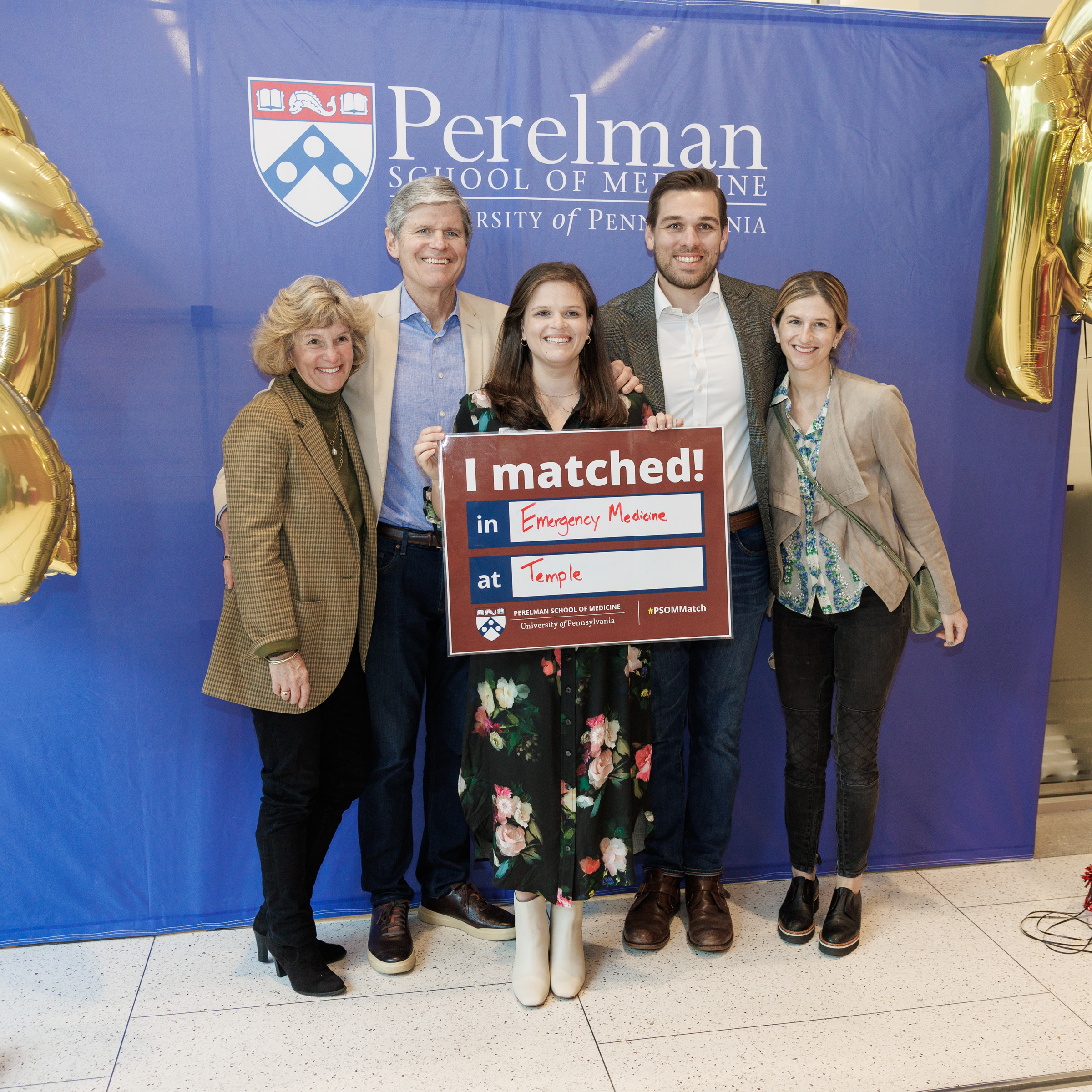 Student holds a sign with her match information, surrounded by family members