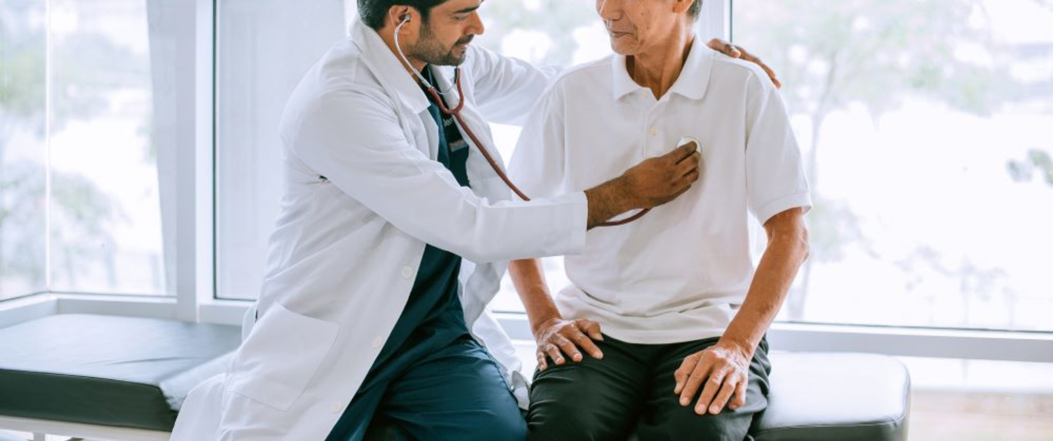 A physician applies a stethoscope to the chest of an older patient