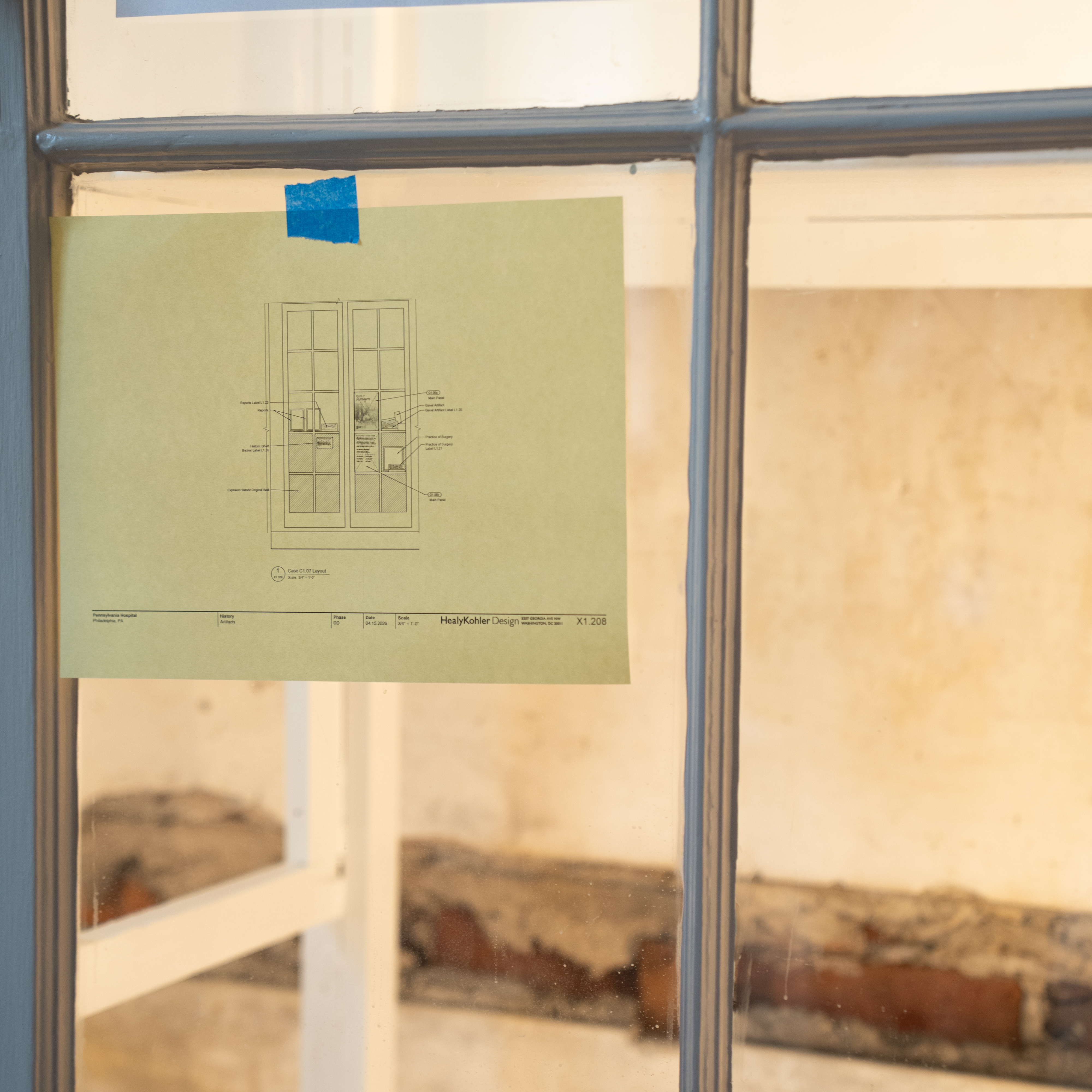 A paper with museum plans taped to a cabinet, with the original exposed wall of the Pennsylvania Hospital Pine Building in the background
